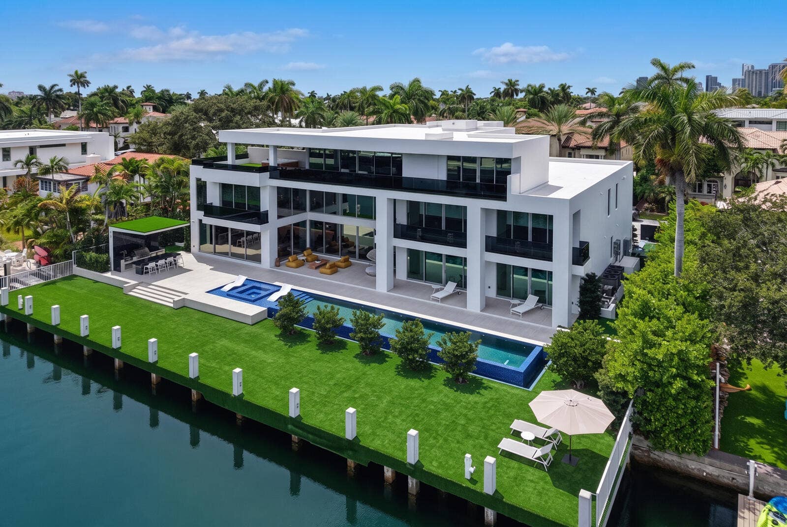 414 ROYAL PLAZA Drive, Fort Lauderdale, FL 33301 Spectacular waterfront setting featuring a 75-foot infinity-edge pool with integrated spa and submerged sun shelf, a covered summer kitchen and barbecue area, expansive outdoor living spaces, and a turf-finished concrete dock extending approximately 20 feet beyond the seawall.