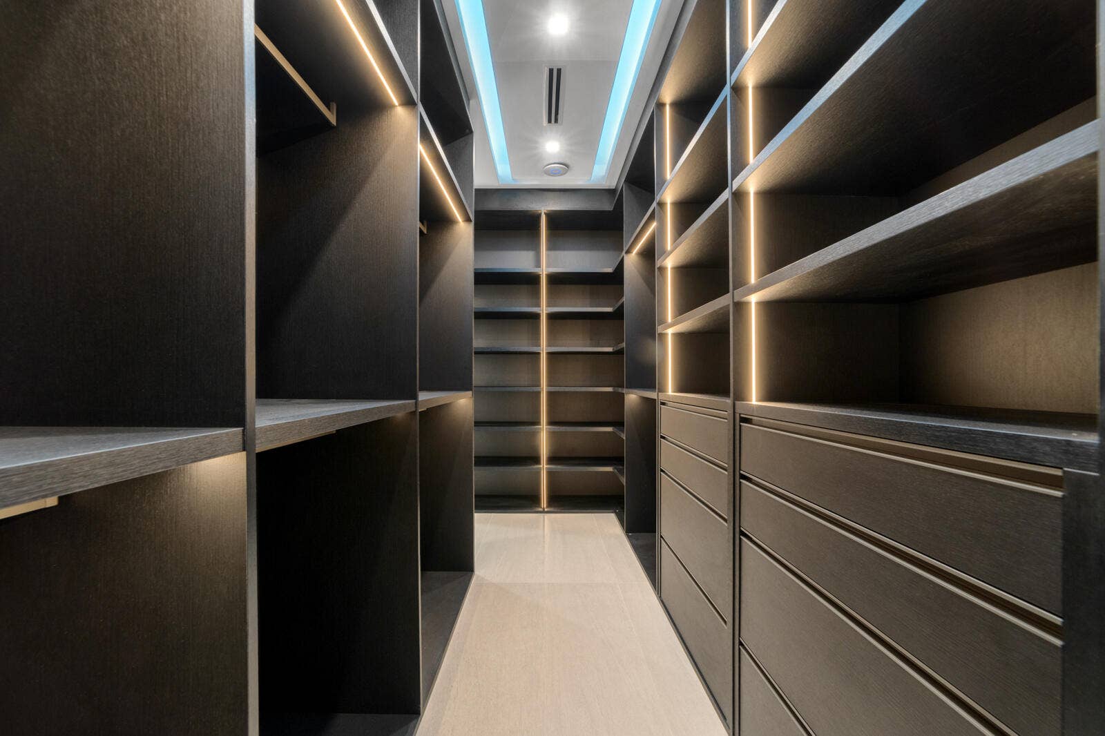 414 ROYAL PLAZA Drive, Fort Lauderdale, FL 33301 Custom gentlemans walk-in wardrobe featuring dark wood cabinetry, extensive shelving and hanging space, integrated drawers, and sophisticated lighting.