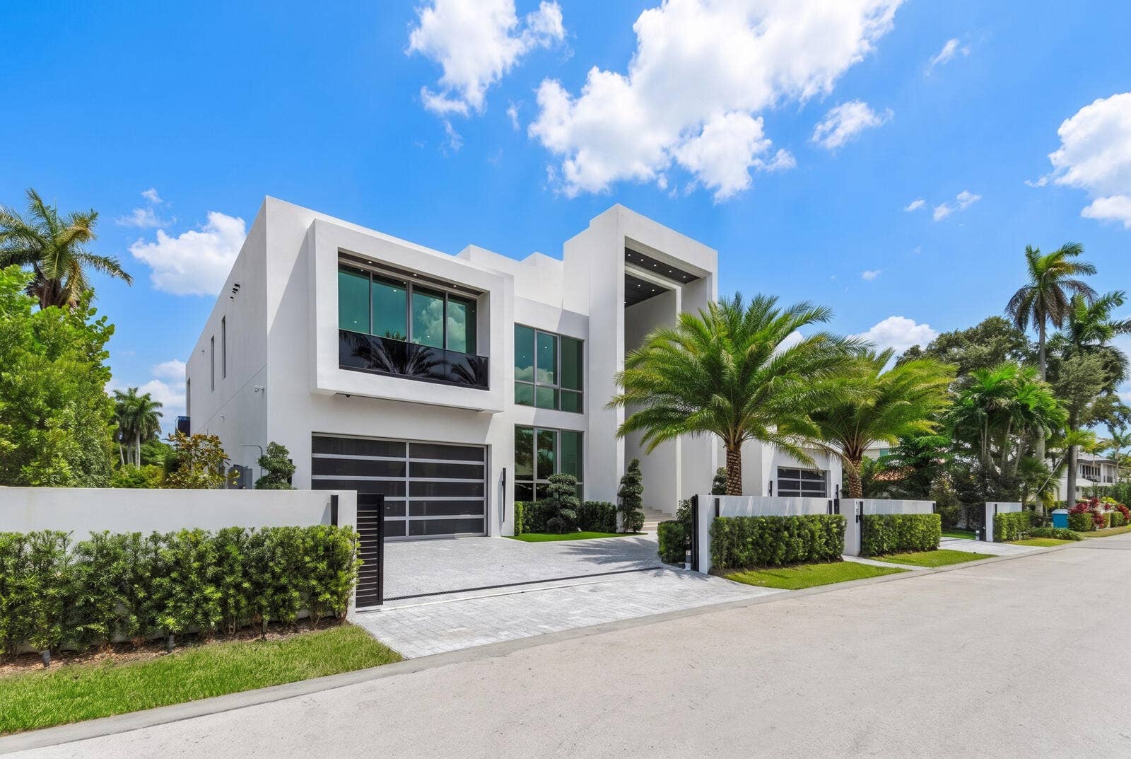 414 ROYAL PLAZA Drive, Fort Lauderdale, FL 33301 Left-side exterior view showcasing the homes bold modern architecture, expansive floor-to-ceiling glass, sleek garage, gated motor court, and lush tropical landscaping.