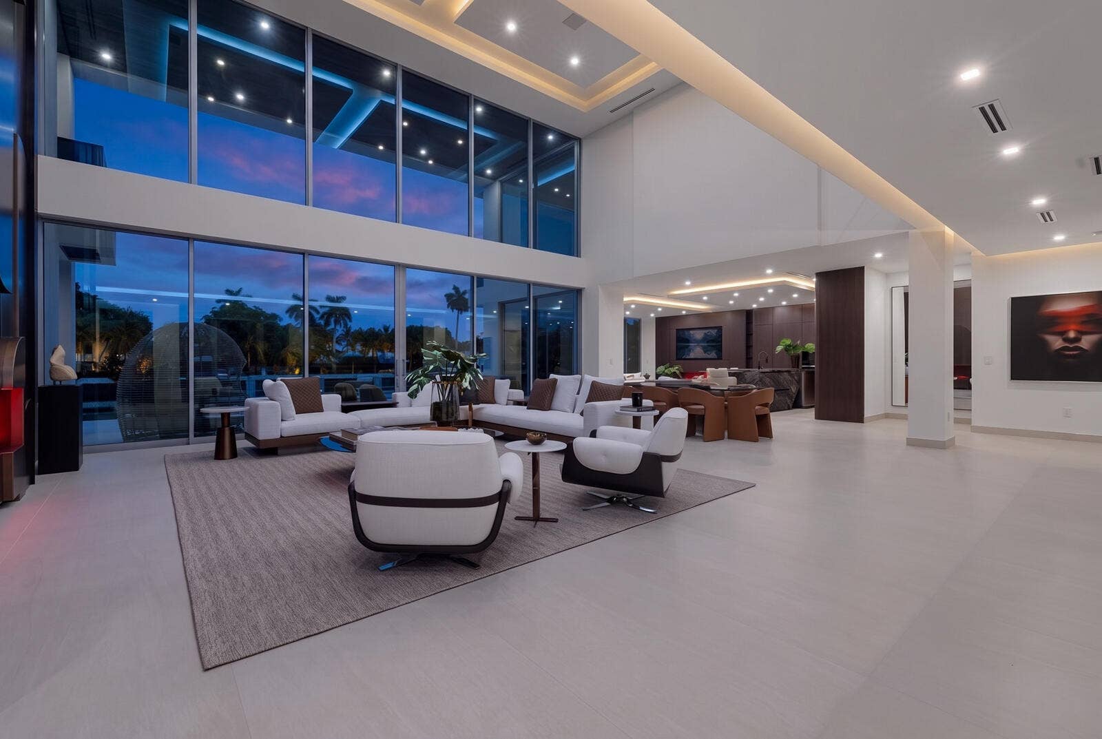 414 ROYAL PLAZA Drive, Fort Lauderdale, FL 33301 Dramatic double-height living room at twilight, featuring soaring walls of glass, expansive waterfront views, sophisticated designer finishes, integrated lighting, and seamless flow into the dining area and chefs kitchen.