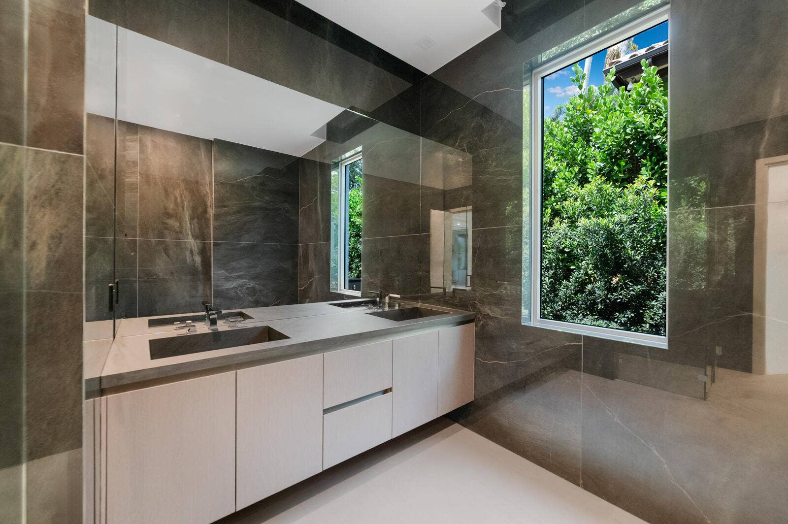 414 ROYAL PLAZA Drive, Fort Lauderdale, FL 33301 Luxurious en-suite bath finished with floor-to-ceiling stone, a floating dual-sink vanity, an oversized mirror, frameless glass shower, and abundant natural light.