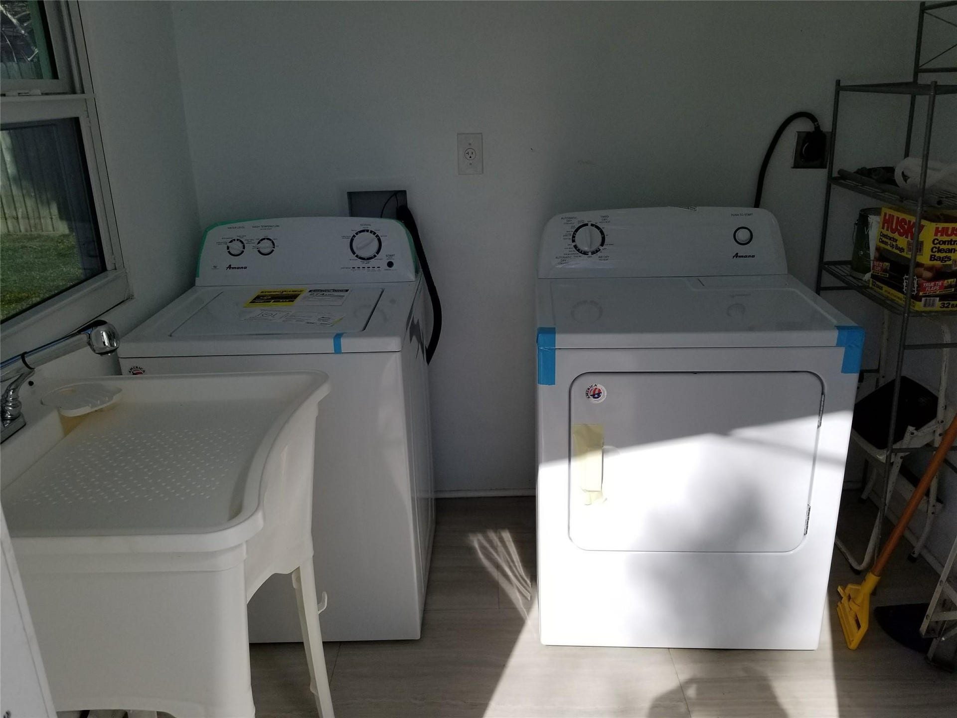 Utility area with a laundry sink, window, and wood-finish flooring