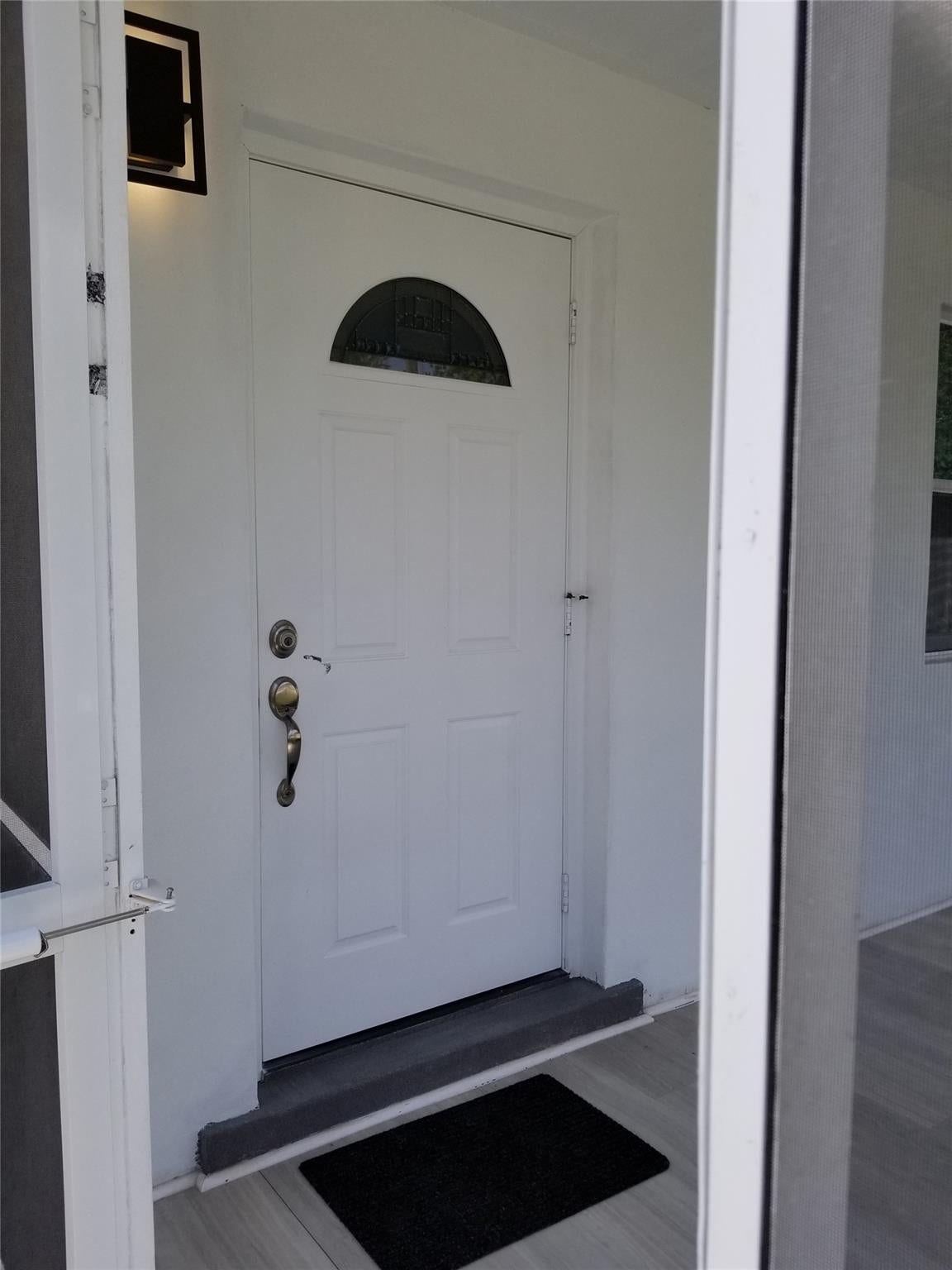 White panel door featuring a decorative transom window and brass hardware