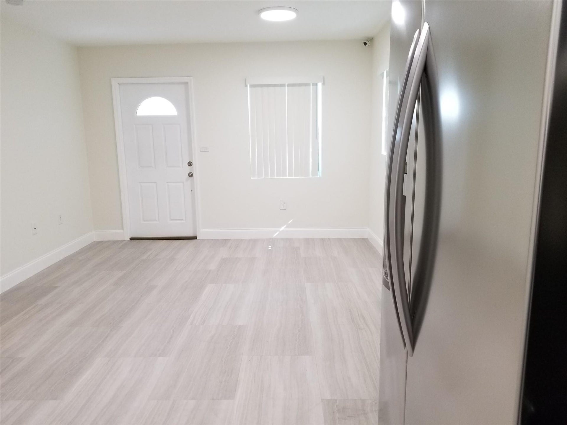 Light wood-finish flooring, white walls, and a recessed ceiling light