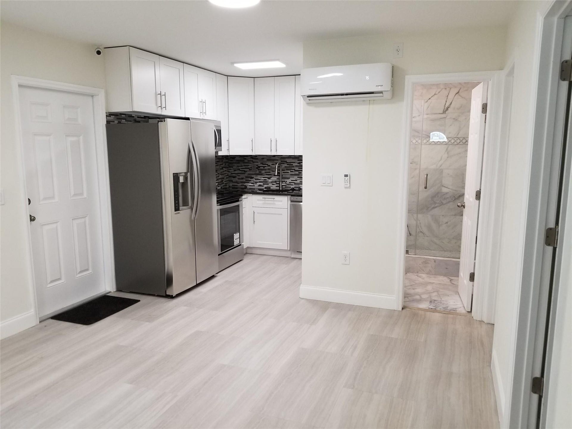 Kitchenette with white cabinetry, stainless steel appliances, and a dark mosaic tile backsplash