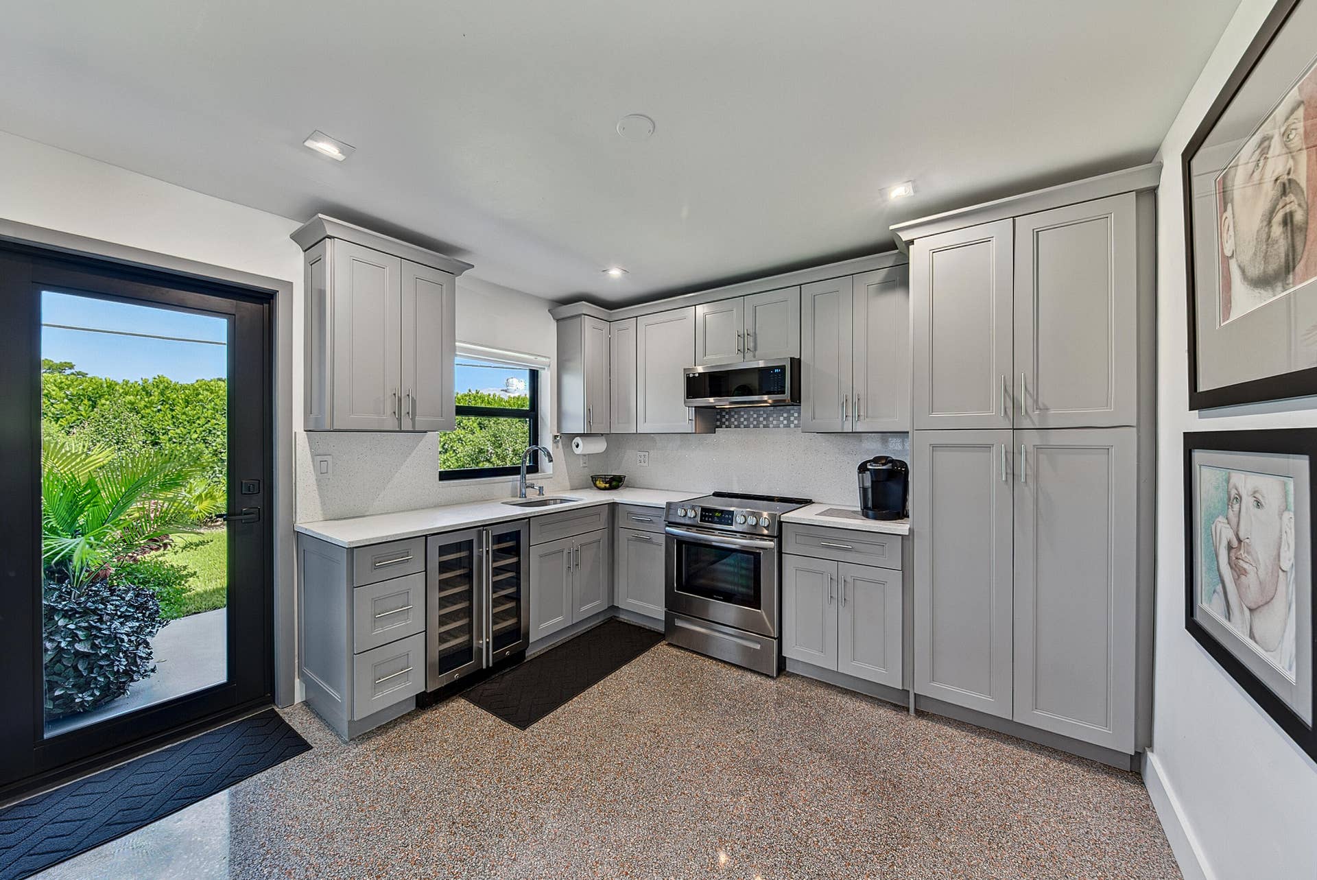4850 NE 5TH Avenue, Oakland Park, FL 33334 Thoughtfully designed kitchen with light gray cabinetry, stainless steel appliances, a built-in wine refrigerator, and quartz countertops.