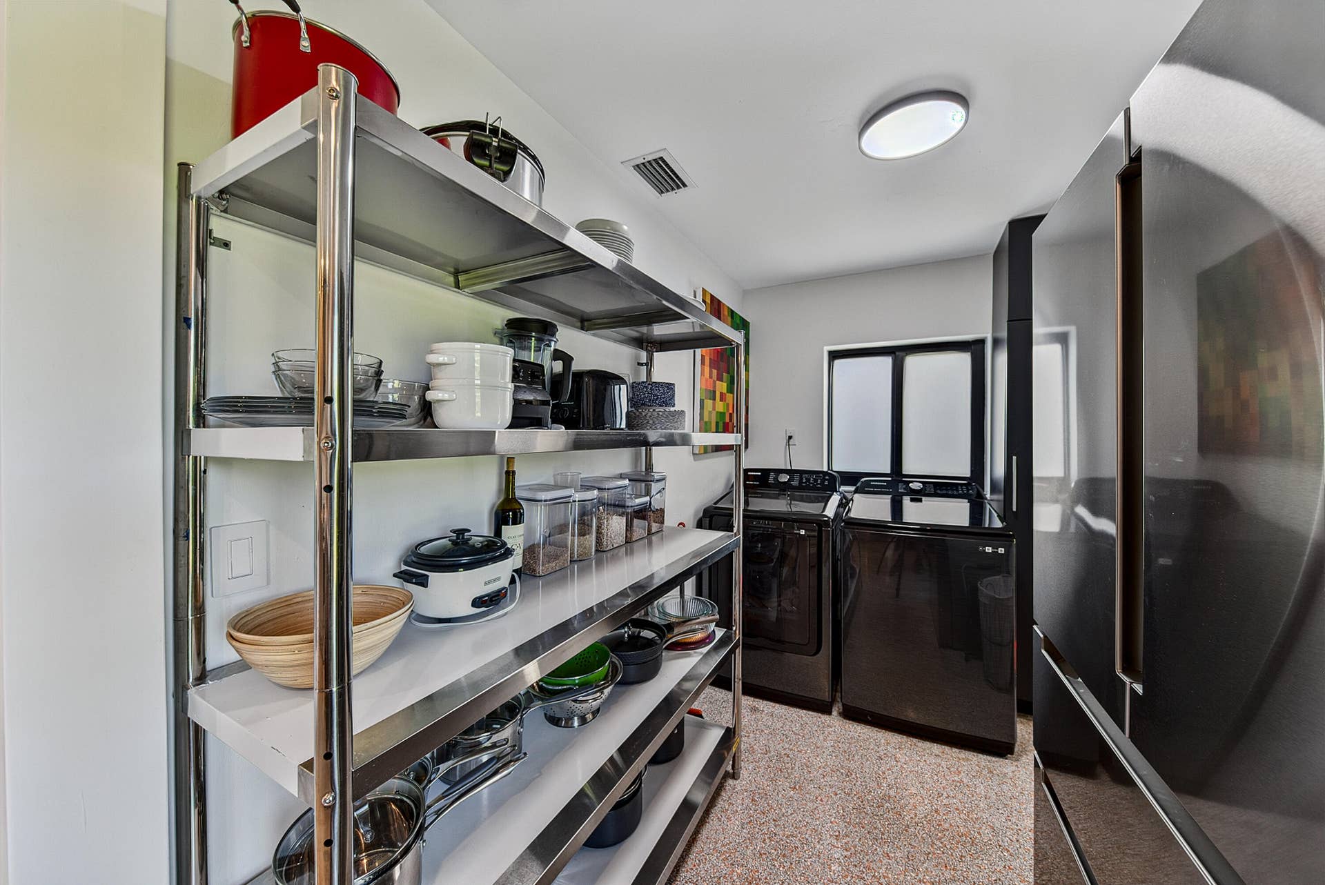 4850 NE 5TH Avenue, Oakland Park, FL 33334 Laundry room has built-in open shelving, custom black storage cabinets