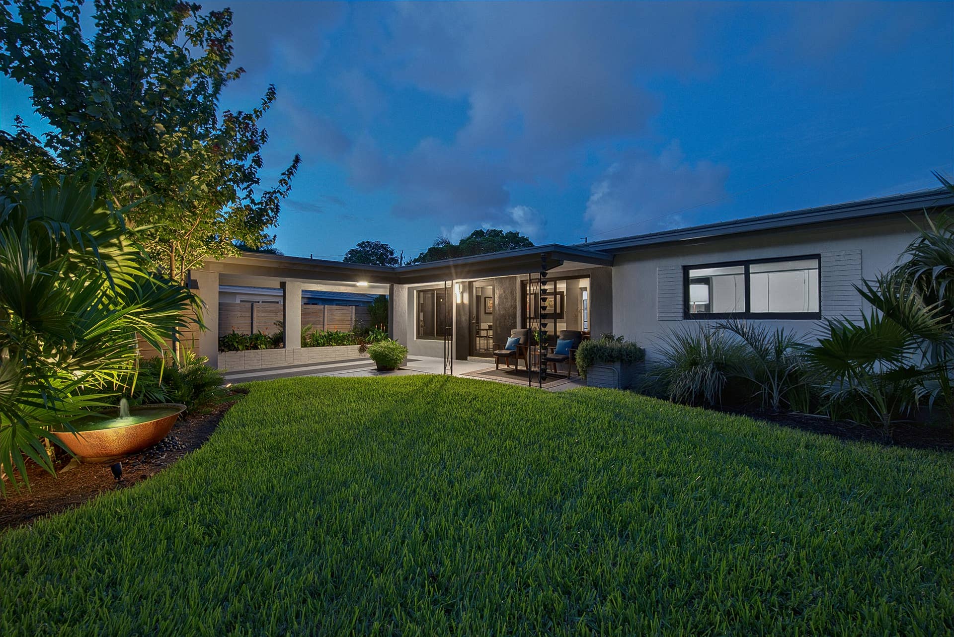 4850 NE 5TH Avenue, Oakland Park, FL 33334 Expansive lawn area, covered patio, integrated planter boxes, modern exterior lighting, and a decorative water feature