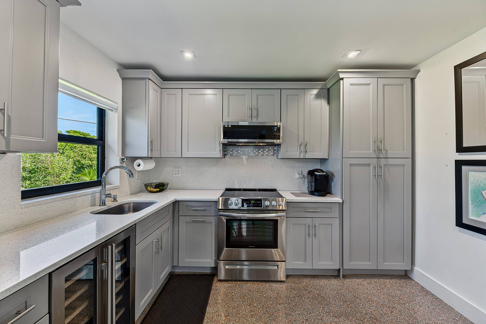 4850 NE 5TH Avenue, Oakland Park, FL 33334 Thoughtfully designed kitchen with light gray cabinetry, stainless steel appliances, a built-in wine refrigerator, and quartz countertops.