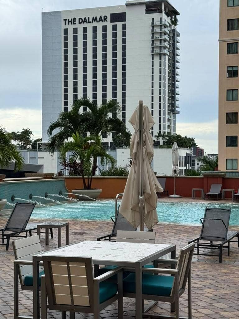 Pool deck featuring brick paving, a swimming pool with water features, and lounge seating