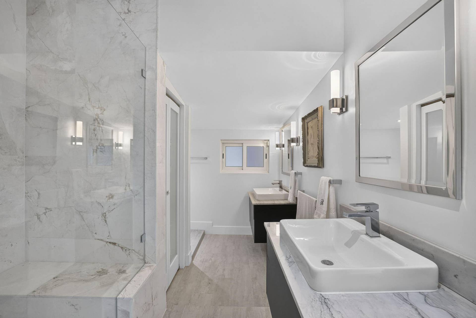 Glass-enclosed shower with a built-in bench, dual rectangular vessel sinks, and tile flooring