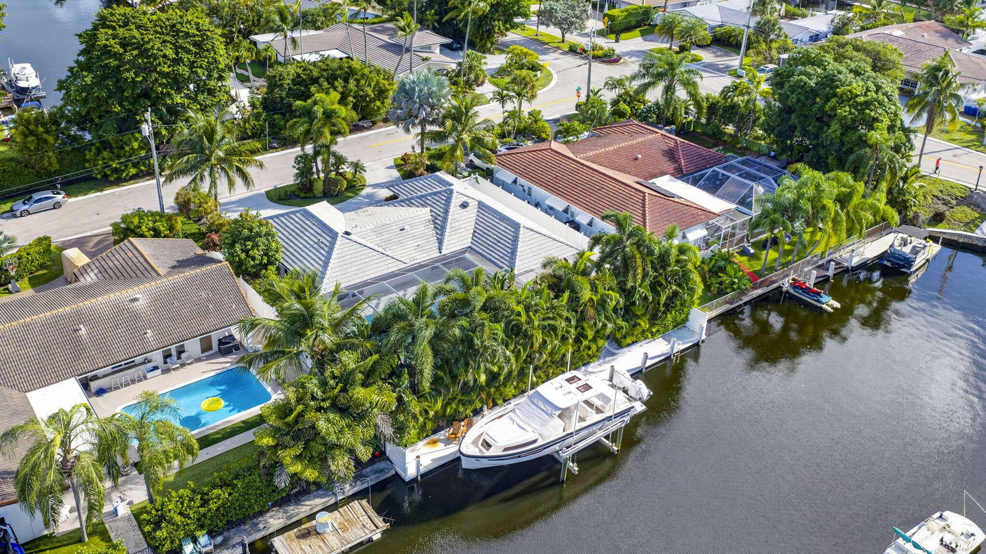 Waterfront property with private boat dock, adjacent swimming pool, and lush landscaping