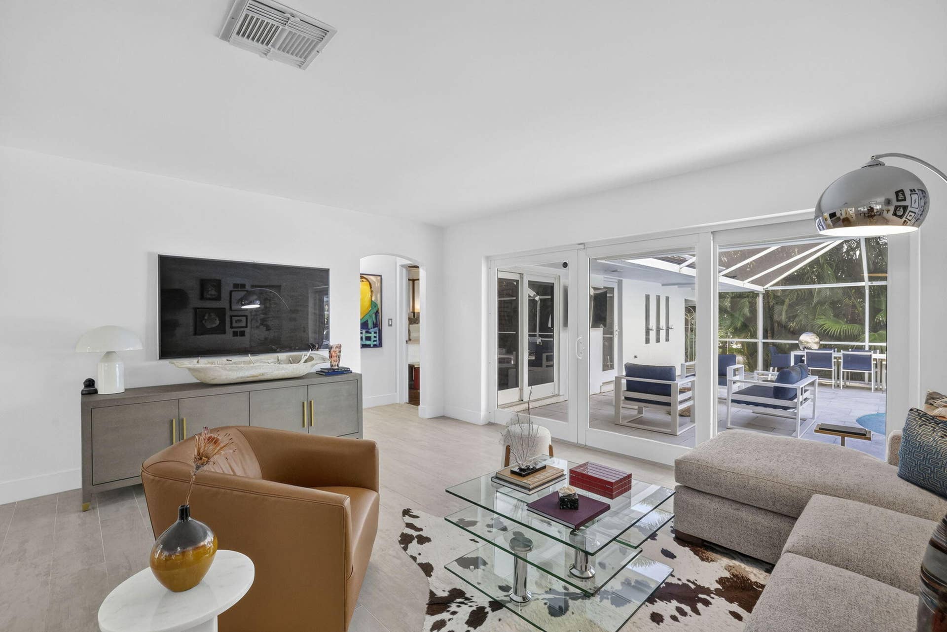 Tile flooring throughout, white walls, arched doorway, sliding glass doors, screened outdoor patio