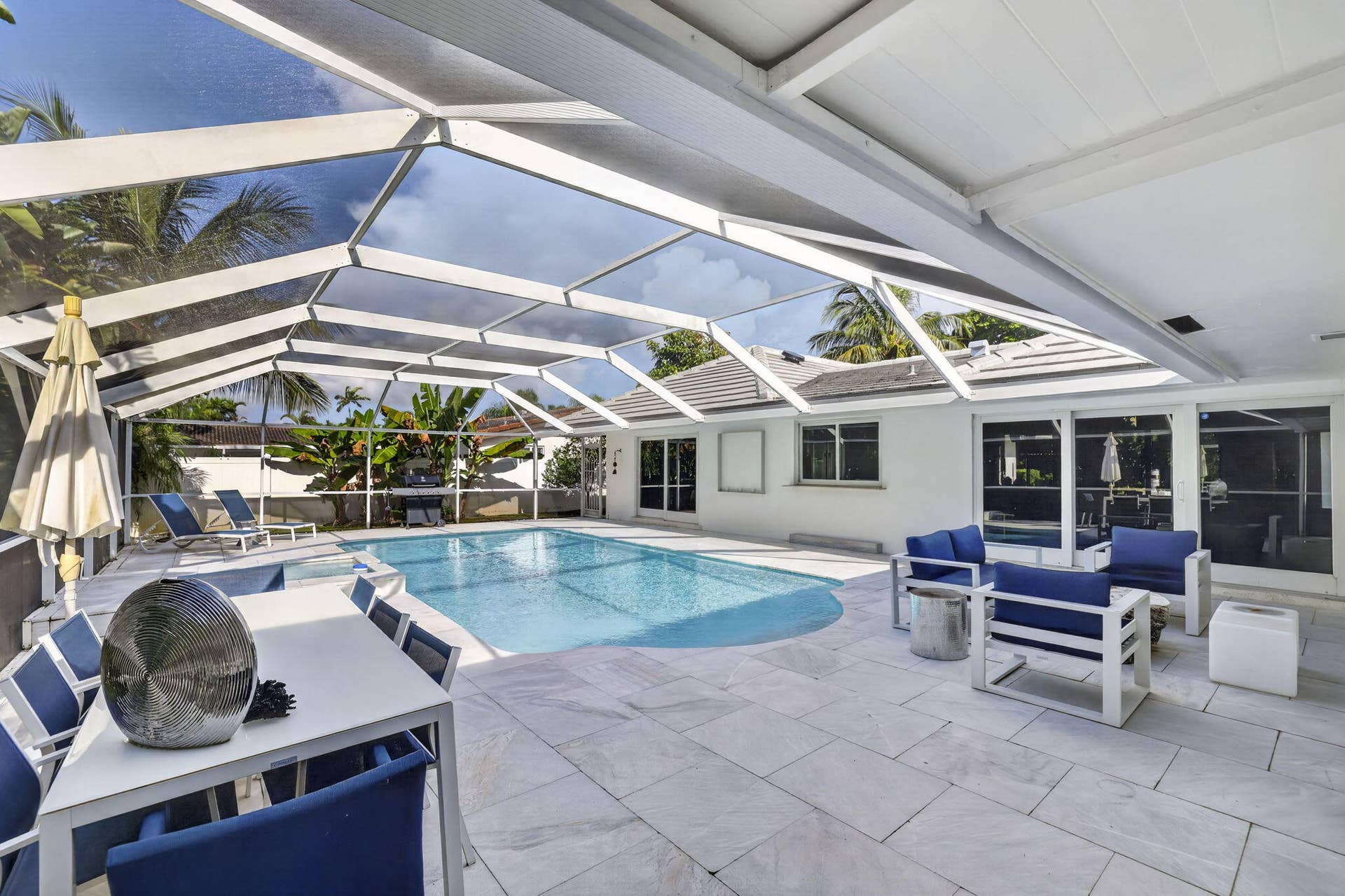 Screened outdoor living area featuring a swimming pool, spacious tiled patio, and covered dining area
