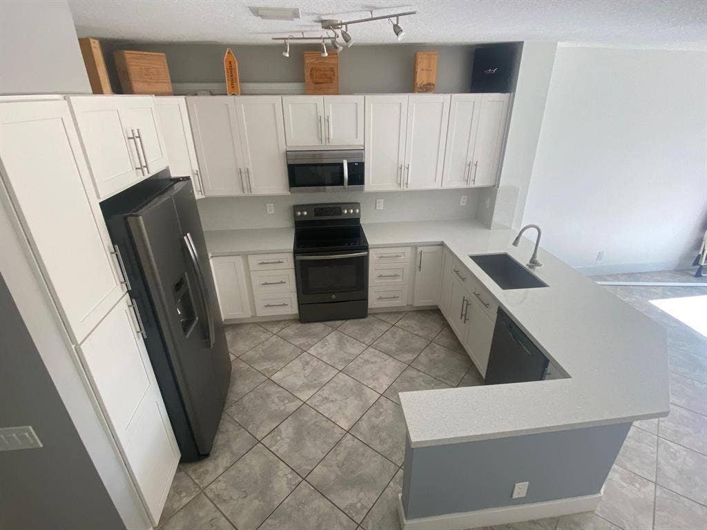 791 NW 42ND Place, Deerfield Beach, Deerfield Beach, FL 33064 U-shaped kitchen with white cabinetry, light-toned countertops, and stainless steel appliances