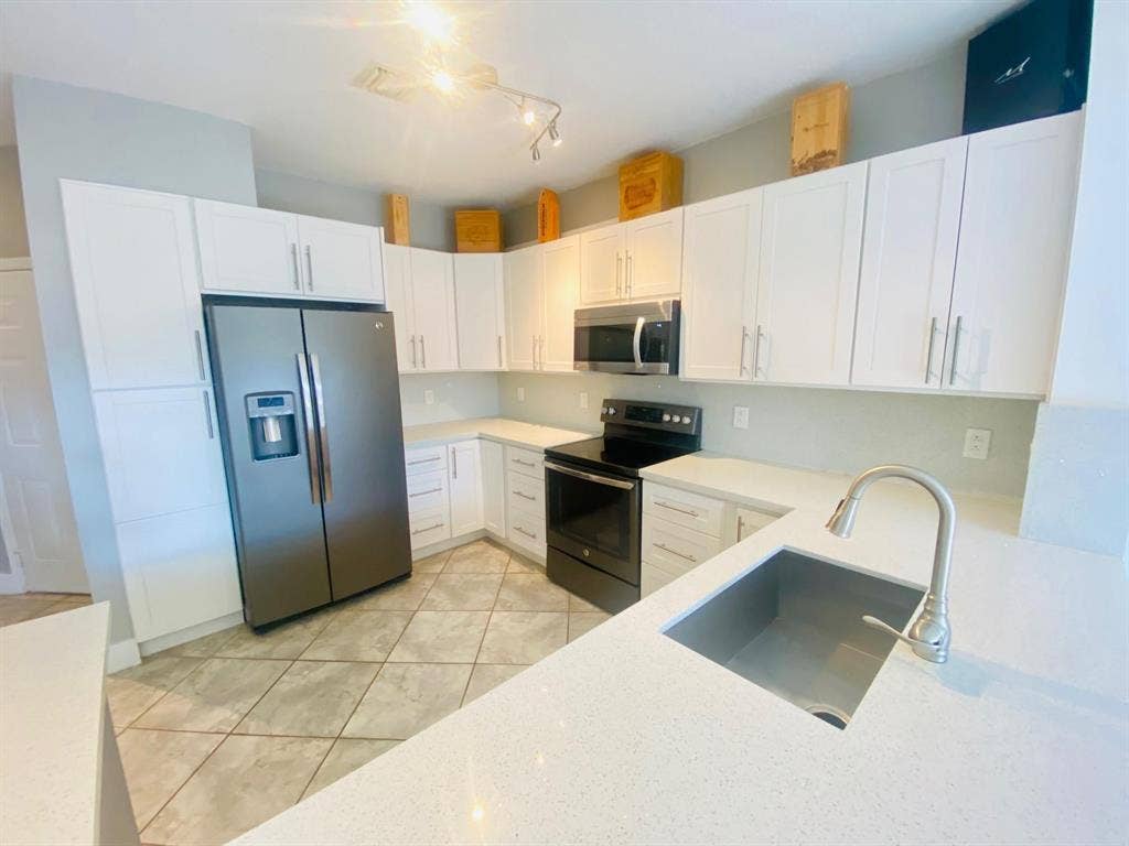 791 NW 42ND Place, Deerfield Beach, Deerfield Beach, FL 33064 White shaker-style cabinetry with brushed nickel hardware, stainless steel appliances, sink with a gooseneck faucet, and tiled flooring