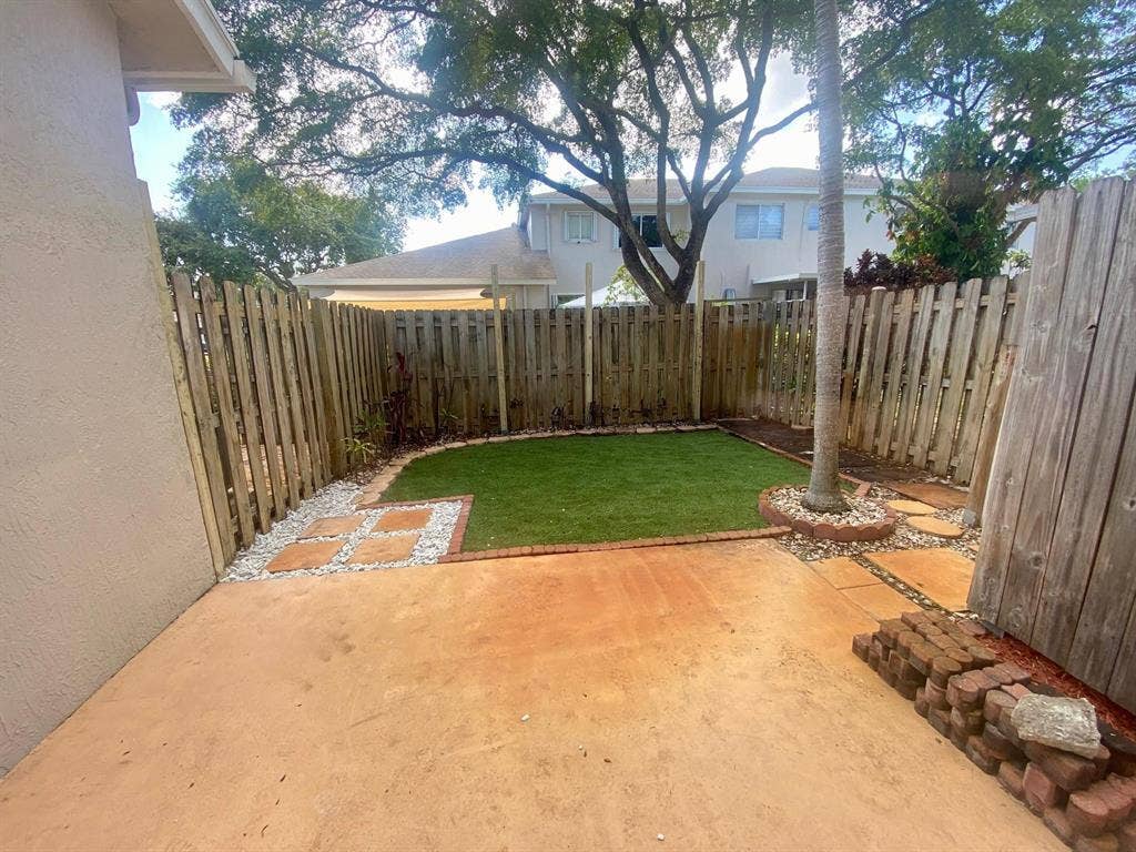 791 NW 42ND Place, Deerfield Beach, Deerfield Beach, FL 33064 Private fenced backyard with concrete surface, artificial turf, and stone paver accents