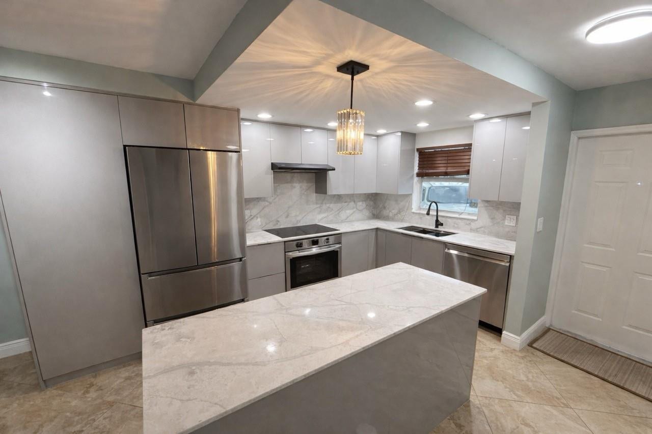809 W Oakland Park Boulevard, #K4, Wilton Manors, FL 33311 Kitchen featuring an island with a light-toned countertop, stainless steel appliances, light gray cabinetry, and a crystal pendant light