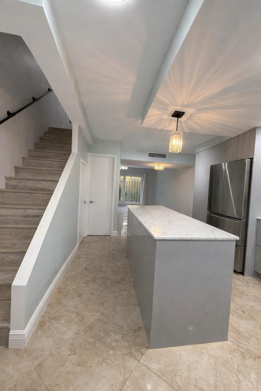 809 W Oakland Park Boulevard, #K4, Wilton Manors, FL 33311 Contemporary kitchen island with a stone countertop, stainless steel refrigerator, recessed lighting, and tile flooring