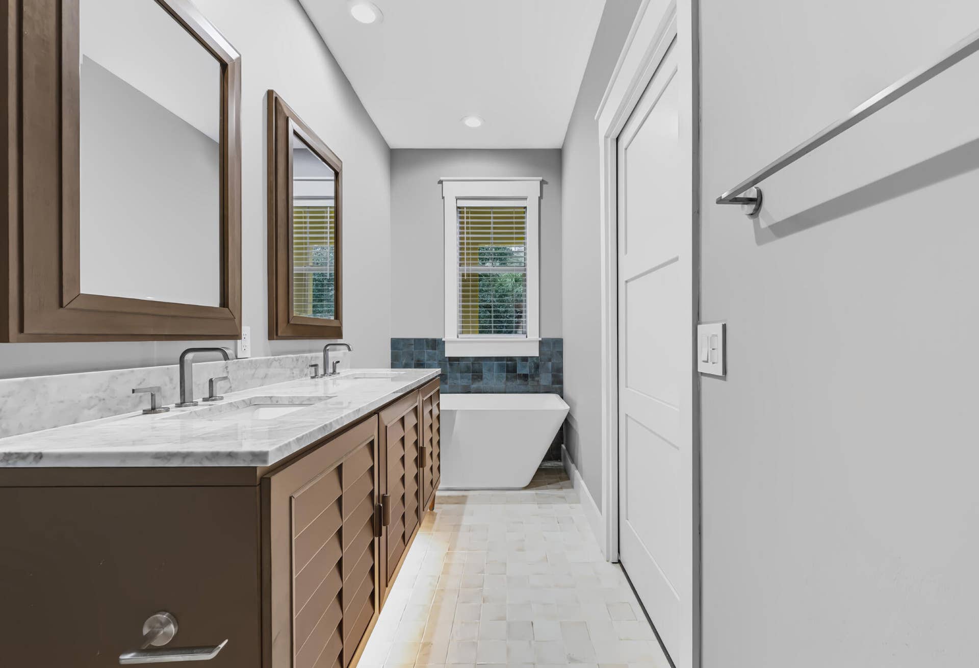 3207 E Community Drive E, Jupiter, FL 33458 Dual vanity with undermount sinks and brushed nickel fixtures, under-cabinet lighting, framed mirrors, a freestanding soaking tub, and tile flooring