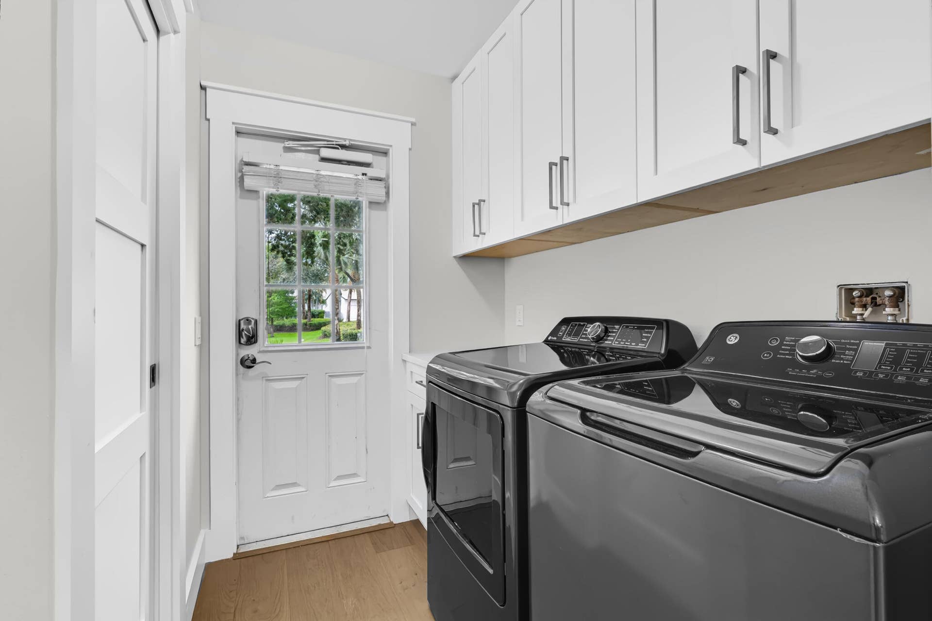 3207 E Community Drive E, Jupiter, FL 33458 White shaker-style cabinetry with dark hardware, a light wood-finish shelf, and wood-finish flooring