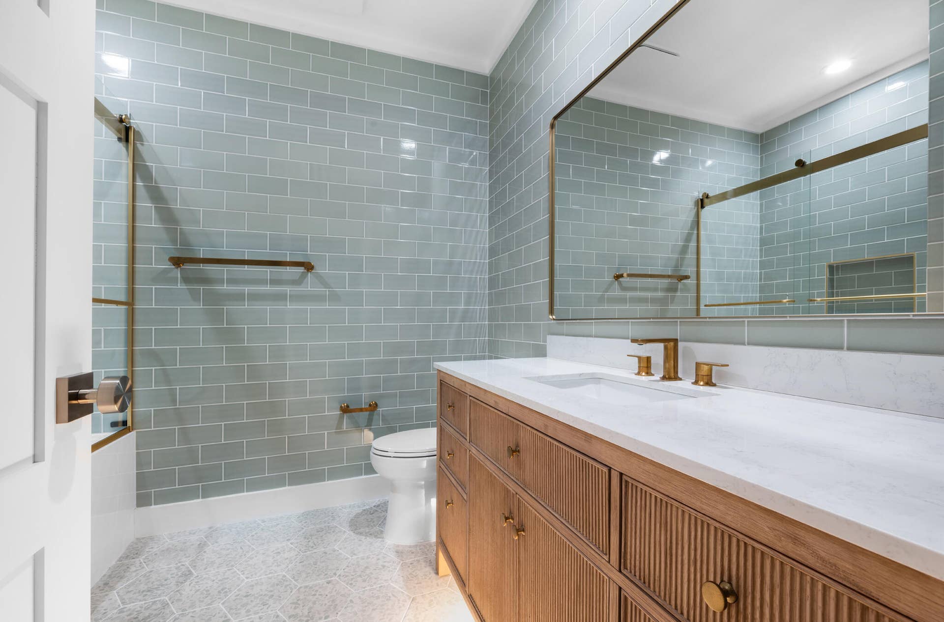 3207 E Community Drive E, Jupiter, FL 33458 Wood-finish vanity with fluted detailing, a white countertop, and gold-tone fixtures