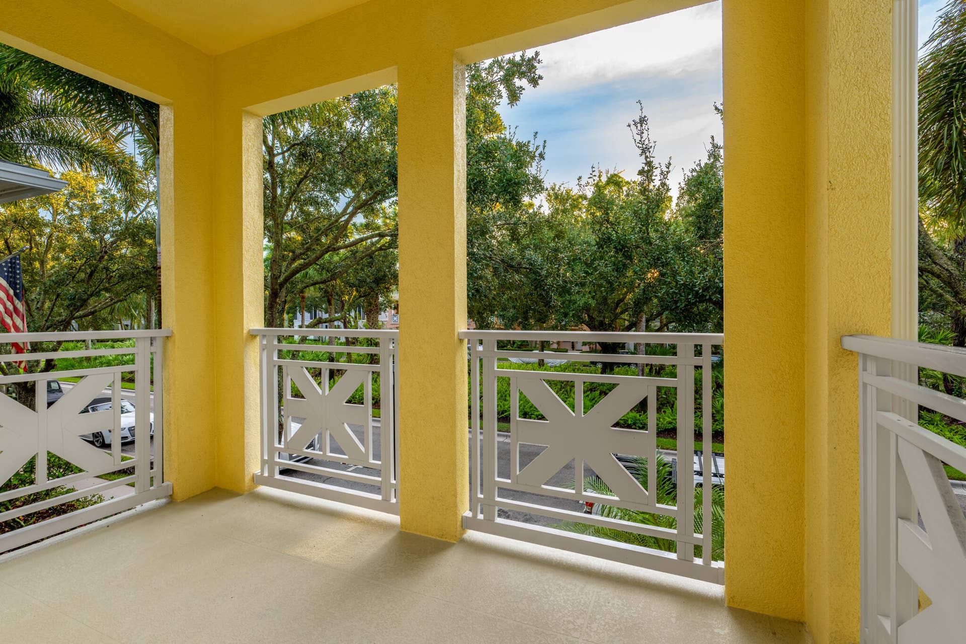 3207 E Community Drive E, Jupiter, FL 33458 Expansive balcony with textured flooring, yellow stucco exterior, and white decorative railings