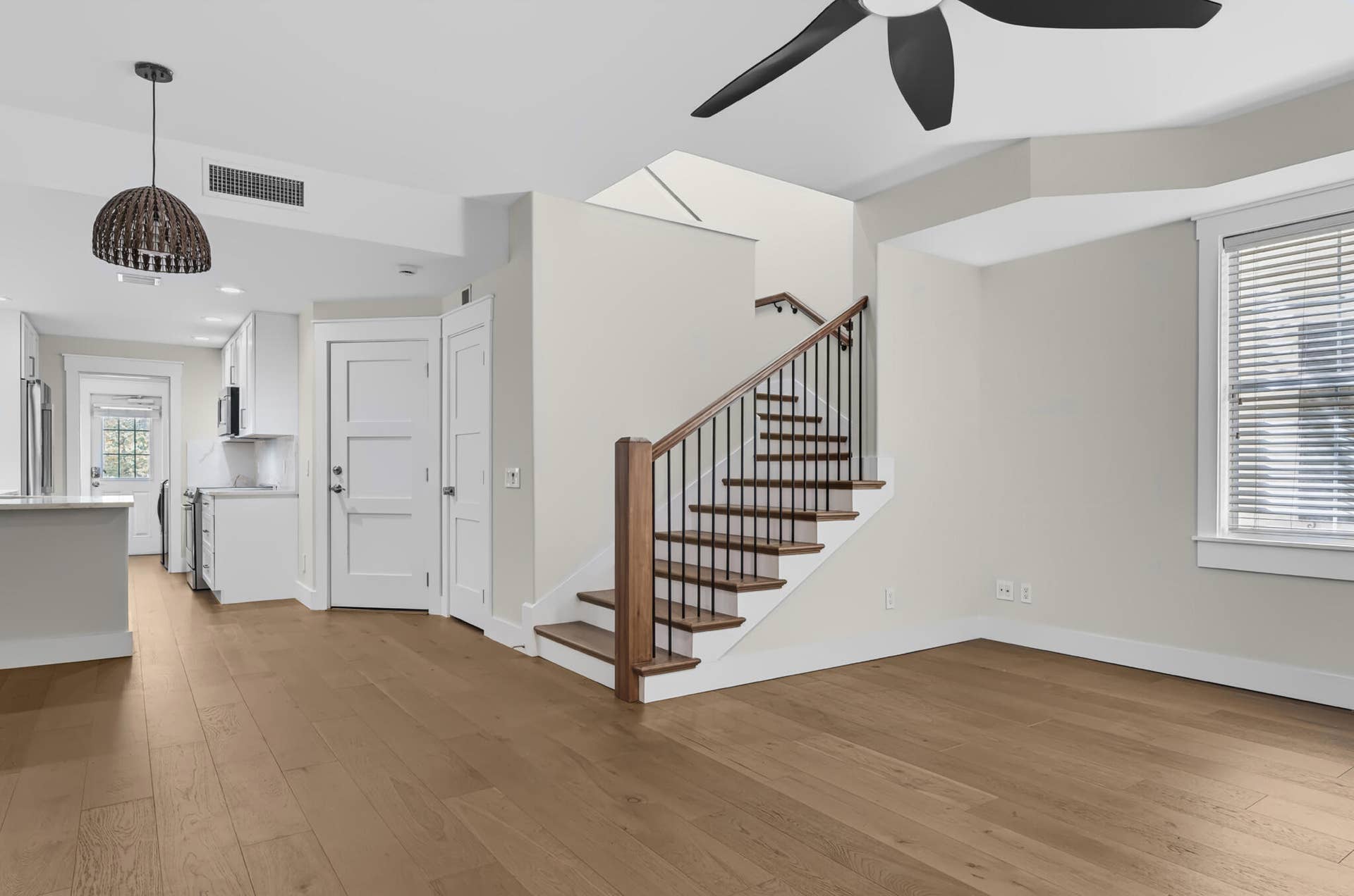 3207 E Community Drive E, Jupiter, FL 33458 Wood-finish flooring, staircase with wood treads and wrought iron balusters, white cabinetry, integrated kitchen appliances, and ceiling fan