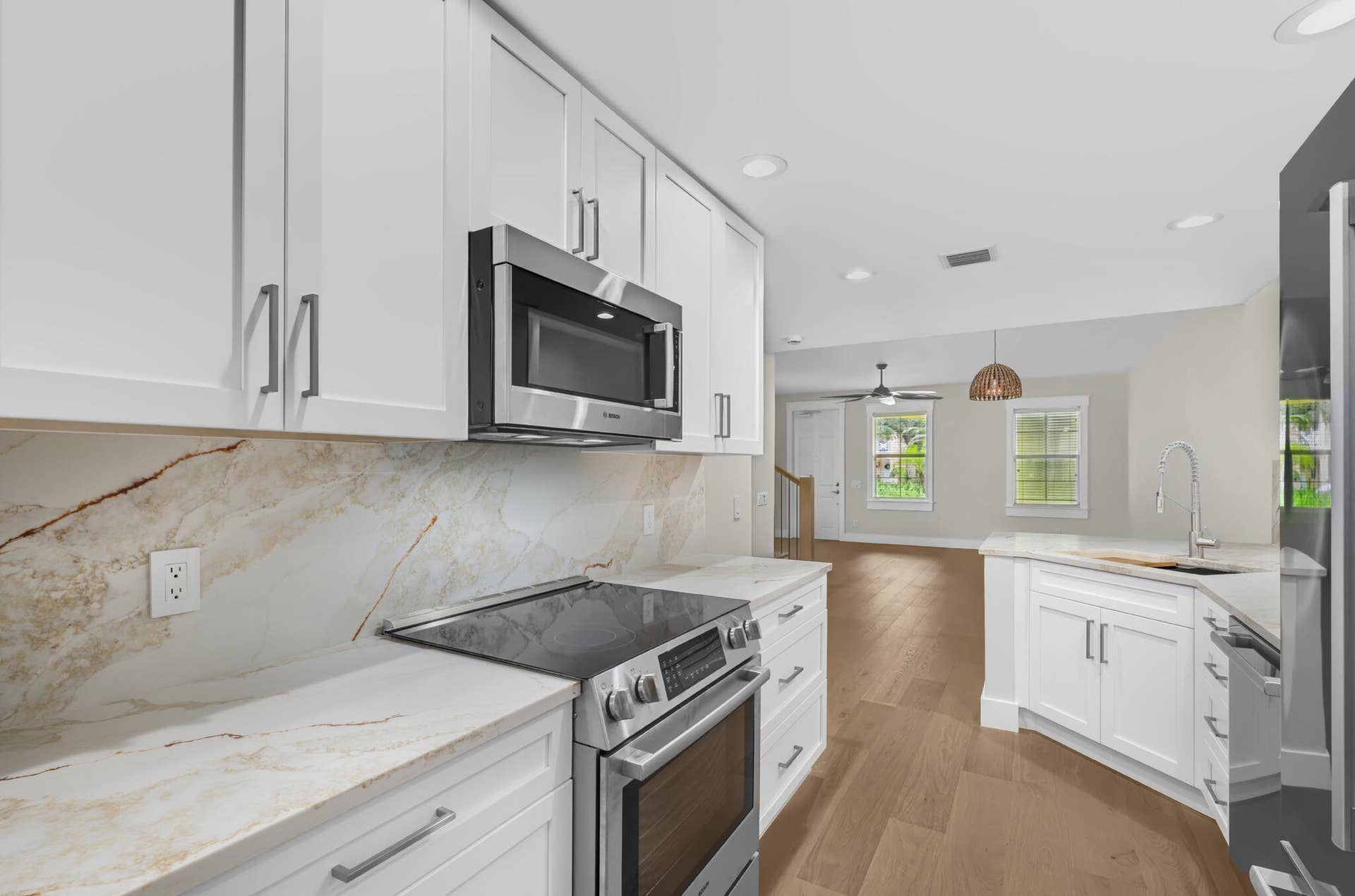 3207 E Community Drive E, Jupiter, FL 33458 Kitchen featuring white shaker-style cabinetry, stainless steel appliances, and light-toned countertops with a matching backsplash