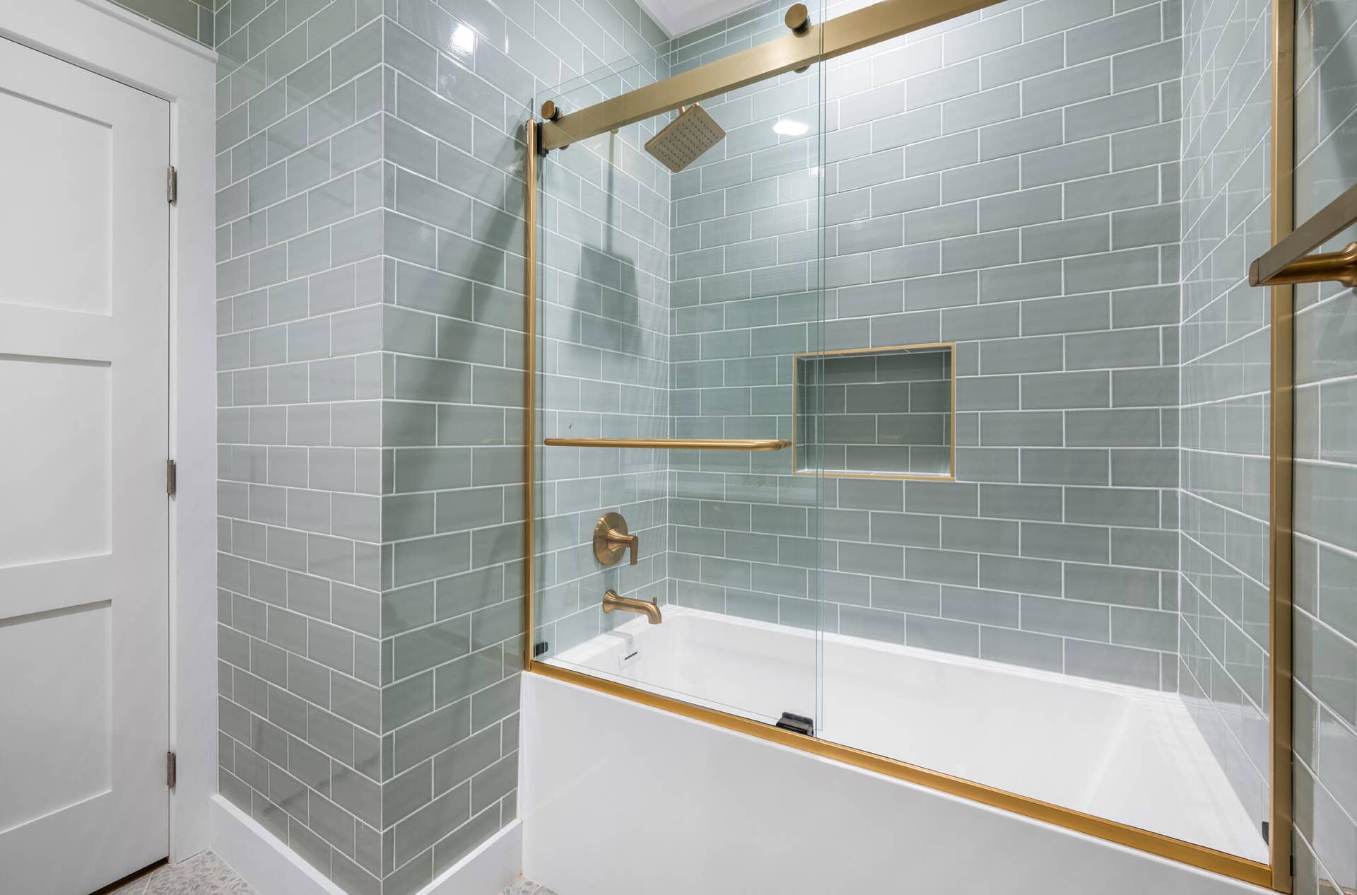 3207 E Community Drive E, Jupiter, FL 33458 Subway tile surround, glass shower enclosure with gold-tone hardware, built-in shower niche, and a tub-shower combination