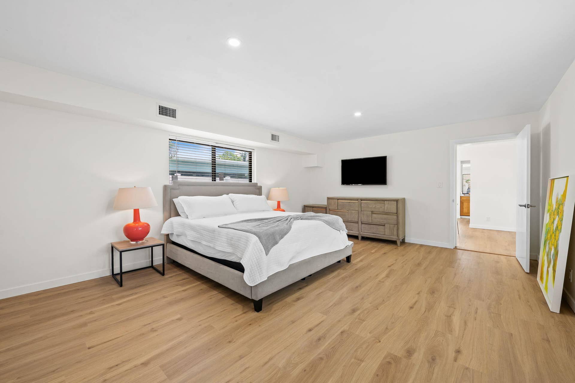 Spacious primary bedroom with hardwood flooring, recessed ceiling lighting, and large windows offering natural light