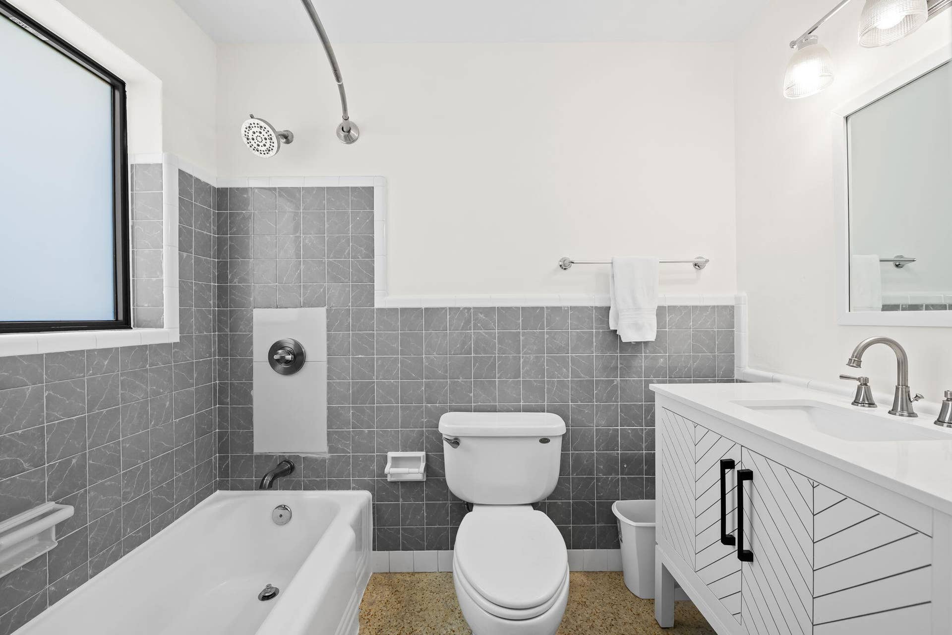 White vanity with a rectangular integrated sink, brushed nickel faucet, and black hardware
