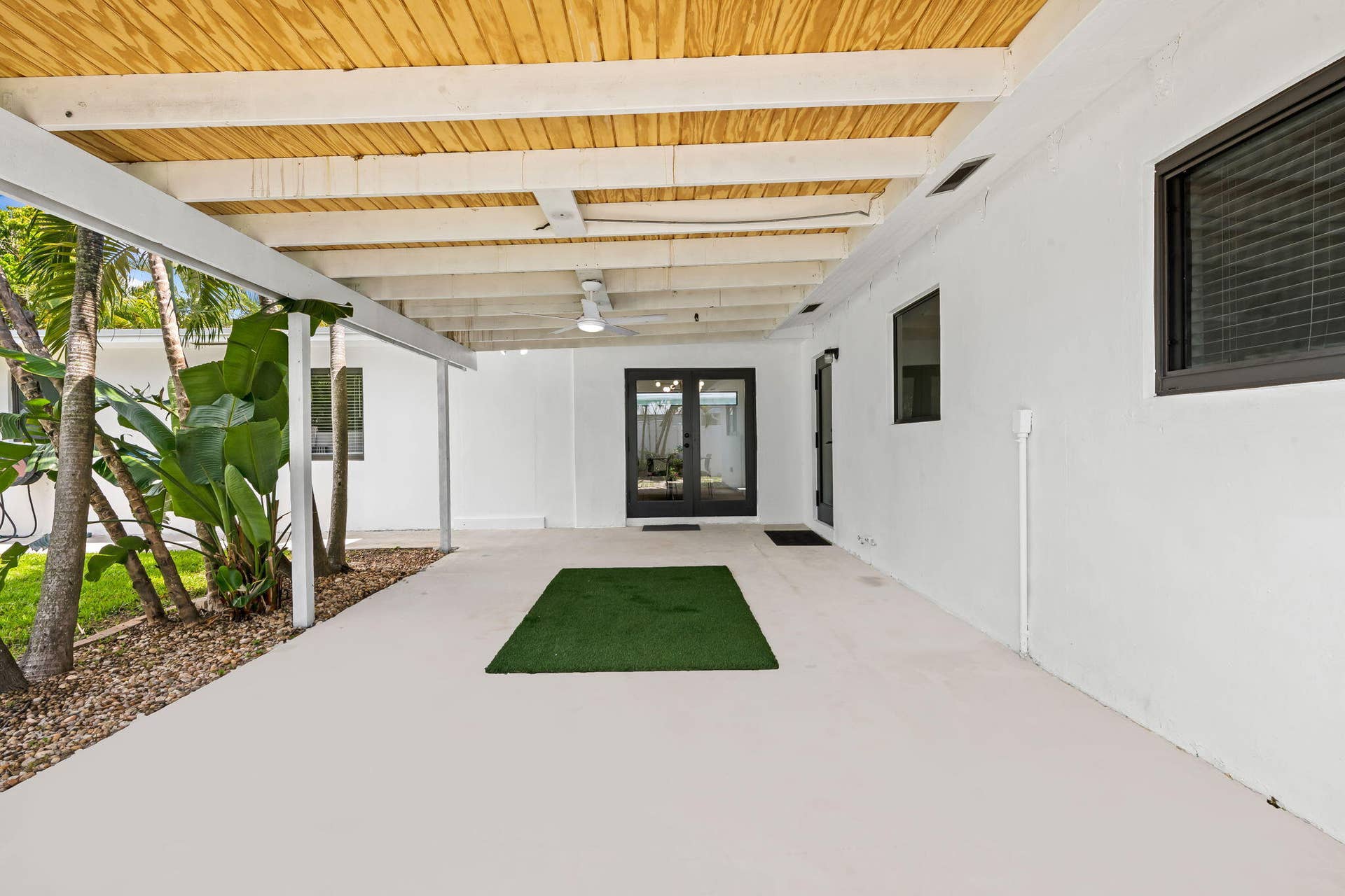 Covered patio with a wood-panel ceiling, ceiling fan, and painted concrete flooring