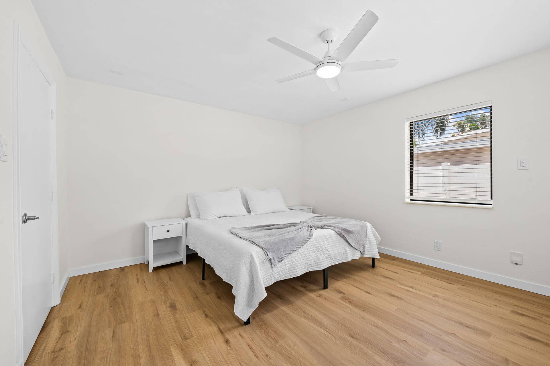 Wood-finish flooring, white walls, and a contemporary ceiling fan with integrated lighting