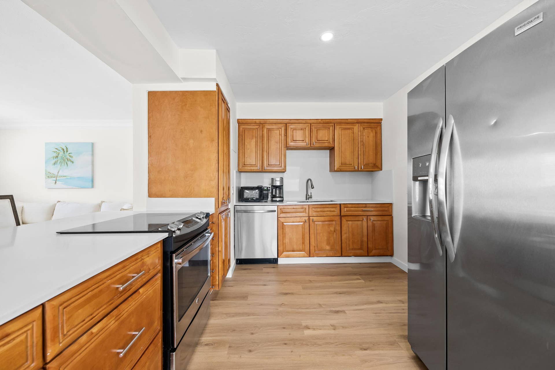 Kitchen featuring wood-finish cabinetry, stainless steel appliances, a white countertop, wood-finish flooring, and recessed lighting