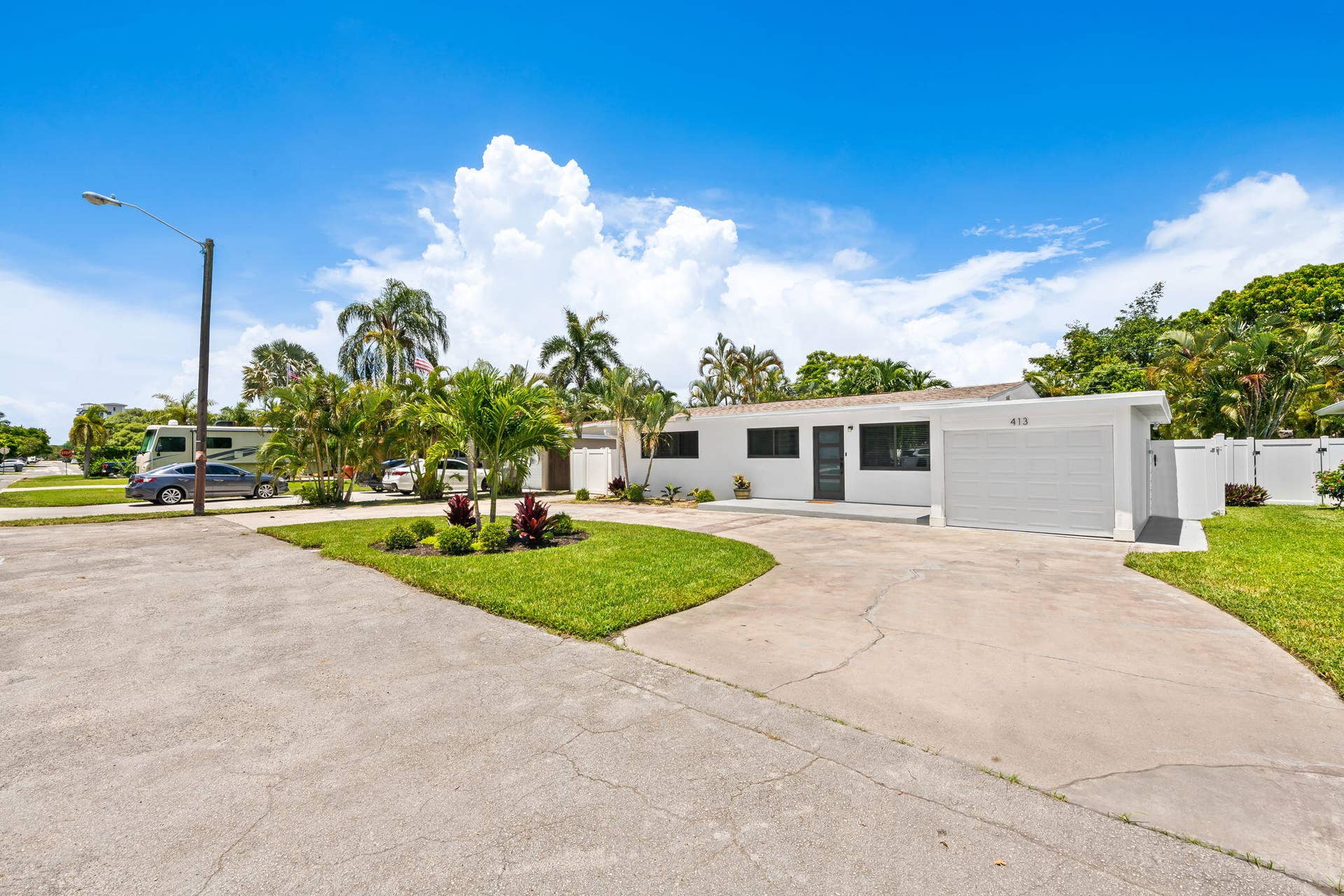 White-painted exterior with dark window frames, an attached garage with a white door, and a concrete driveway