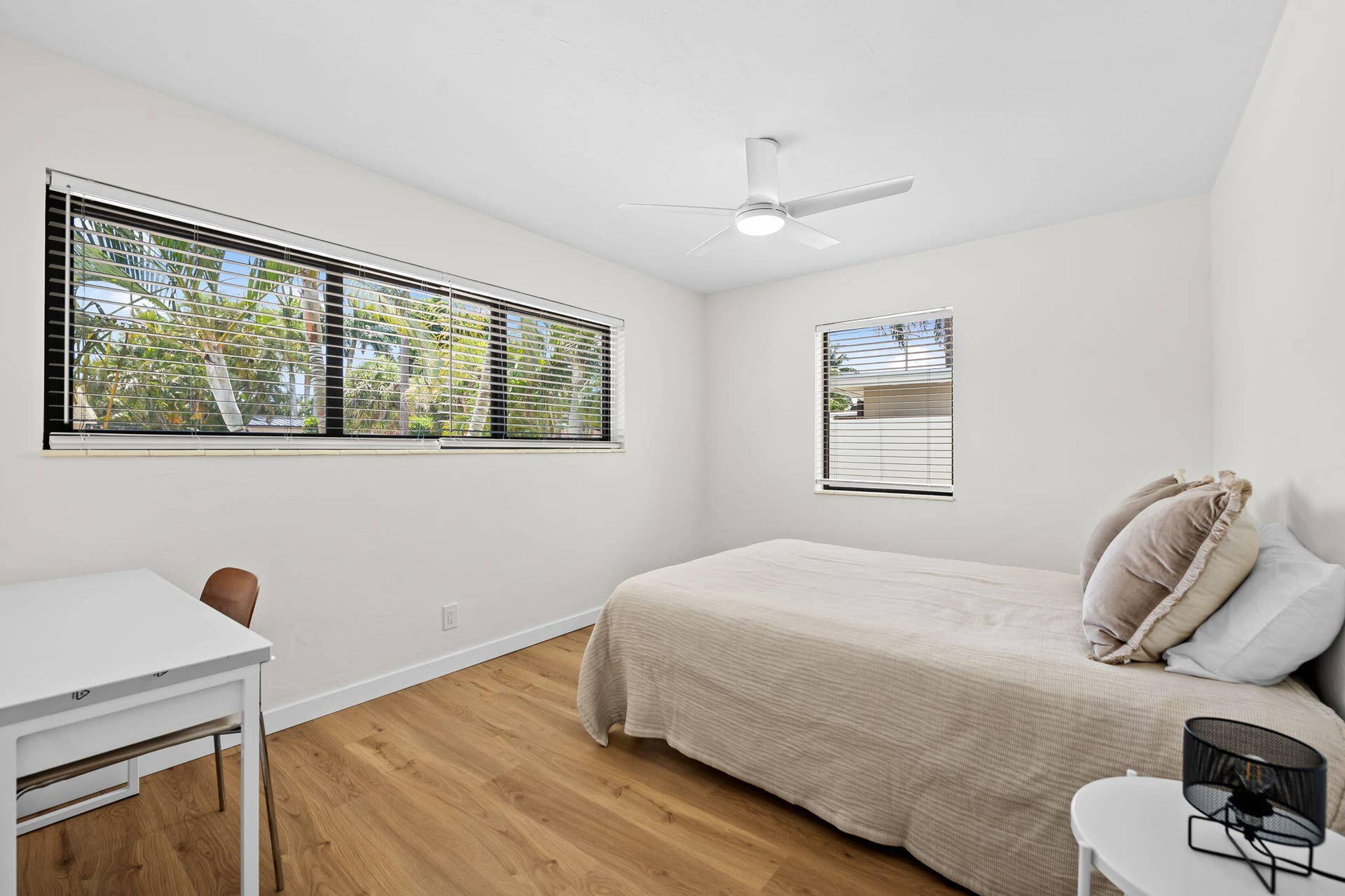 Wood-finish flooring, white walls, horizontal window, additional window, and a ceiling fan