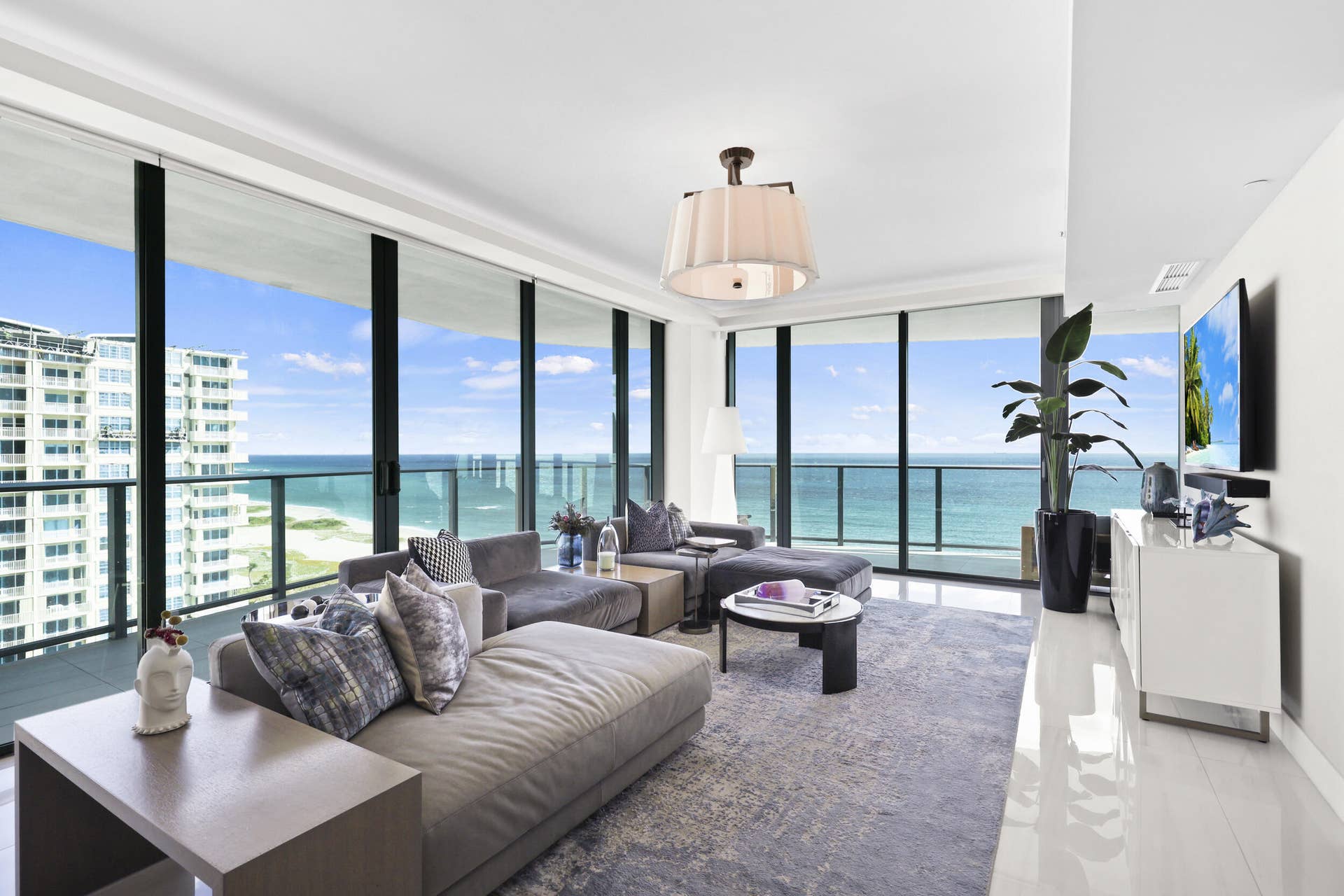 730 N Ocean Boulevard, Pompano Beach, FL 33062 Framed by floor-to-ceiling impact glass, the living room opens seamlessly onto the wraparound balcony, creating an inviting retreat to unwind while enjoying sweeping views and refreshing ocean breezes.