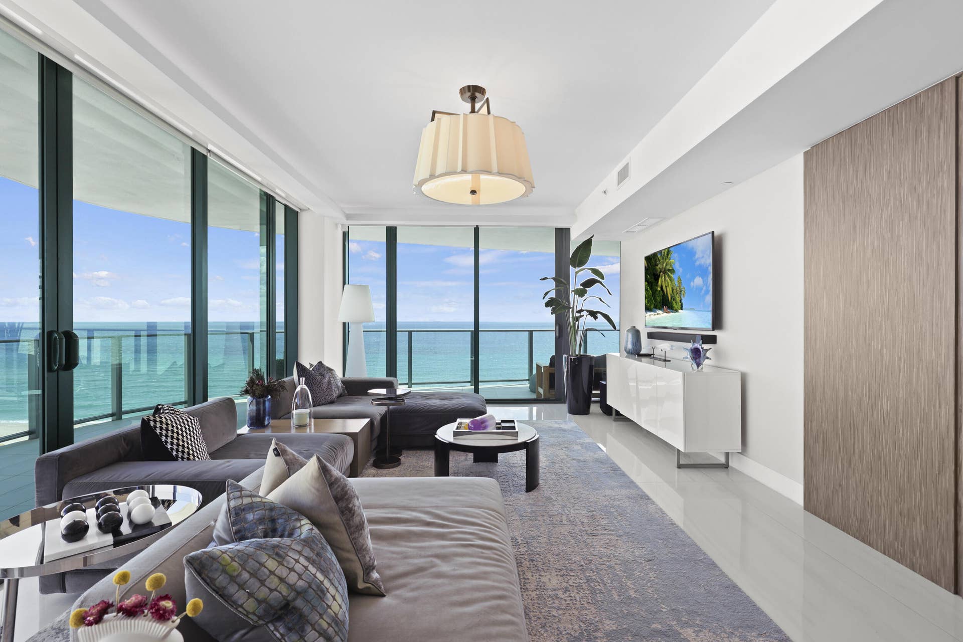 730 N Ocean Boulevard, Pompano Beach, FL 33062 Framed by floor-to-ceiling impact glass, the living room opens seamlessly onto the wraparound balcony, creating an inviting retreat to unwind while enjoying sweeping views and refreshing ocean breezes.