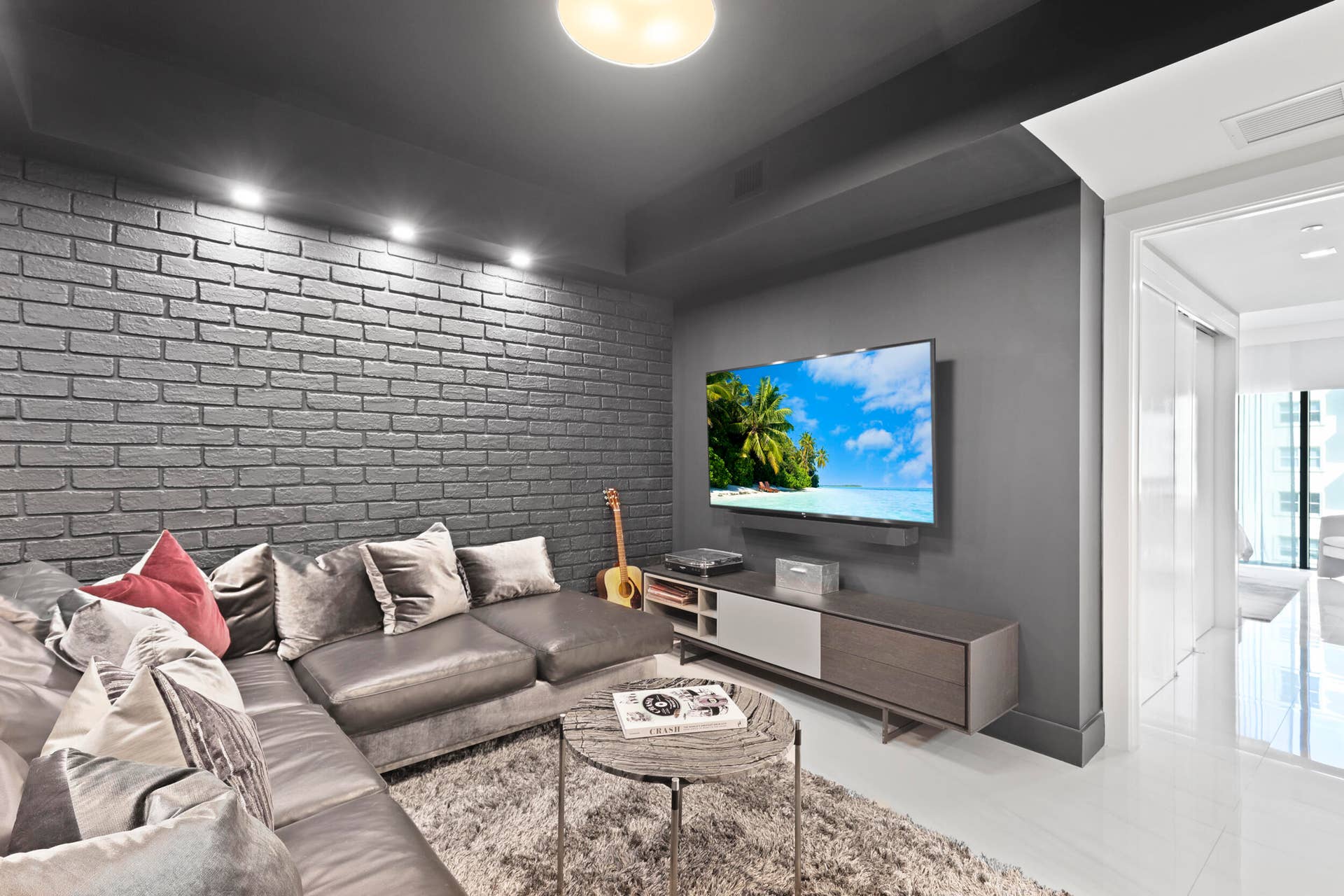 730 N Ocean Boulevard, Pompano Beach, FL 33062 A true showstopper, the den brings bold character and unexpected warmth to this oceanfront residence. A custom faux brick accent wall and dramatic lighting create an unforgettable setting for a movie theater, game room, private office or intimate lounge. Rarely found in a contemporary oceanfront home, this versatile space may also be adapted into a fourth bedroom if desired.