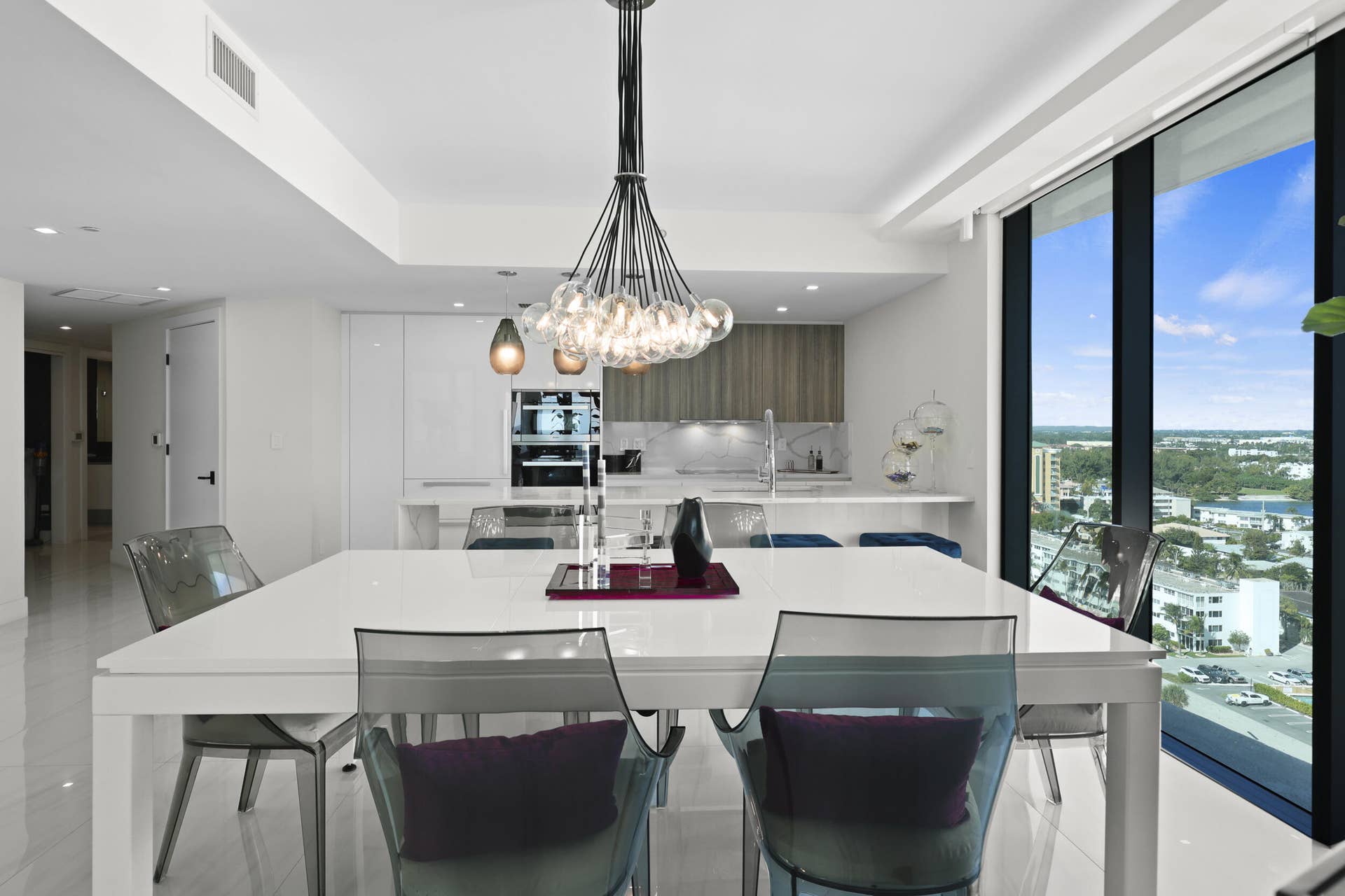 730 N Ocean Boulevard, Pompano Beach, FL 33062 The dining area is illuminated by a designer chandelier and custom accent lighting, all framed by captivating views of the Atlantic Ocean and Intracoastal Waterway.