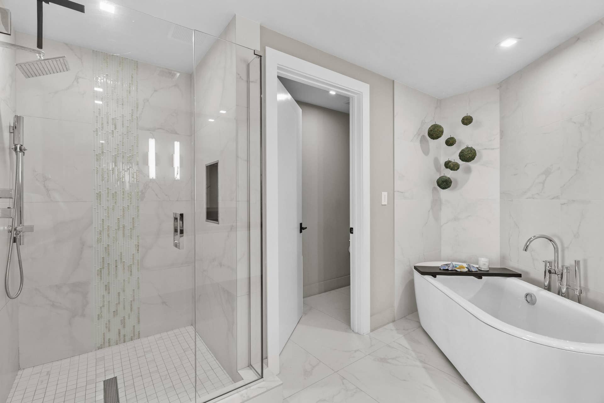 730 N Ocean Boulevard, Pompano Beach, FL 33062 A private spa within the primary suite, this exquisite bathroom showcases custom porcelain tile, a frameless glass shower, a freestanding soaking tub and a floating vanity topped with leathered quartzite, all beautifully illuminated by custom designer sconces.
