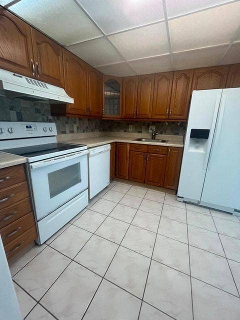 480 EXECUTIVE CENTER Drive, #2F, West Palm Beach, West Palm Beach, FL 33401 Kitchen featuring wood cabinetry, white appliances, tile flooring, and a tile backsplash