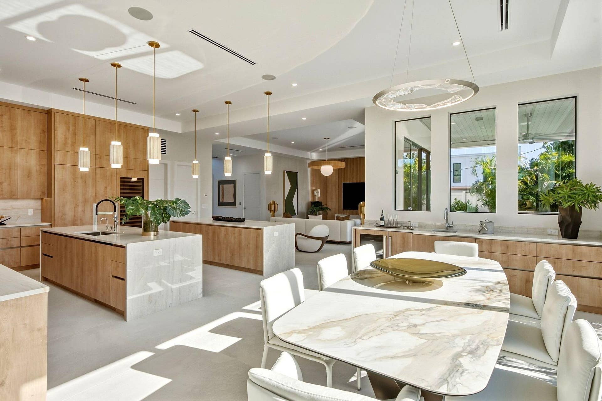 Open-concept kitchen and dining area featuring dual islands with waterfall countertops, integrated appliances, and floor-to-ceiling cabinetry