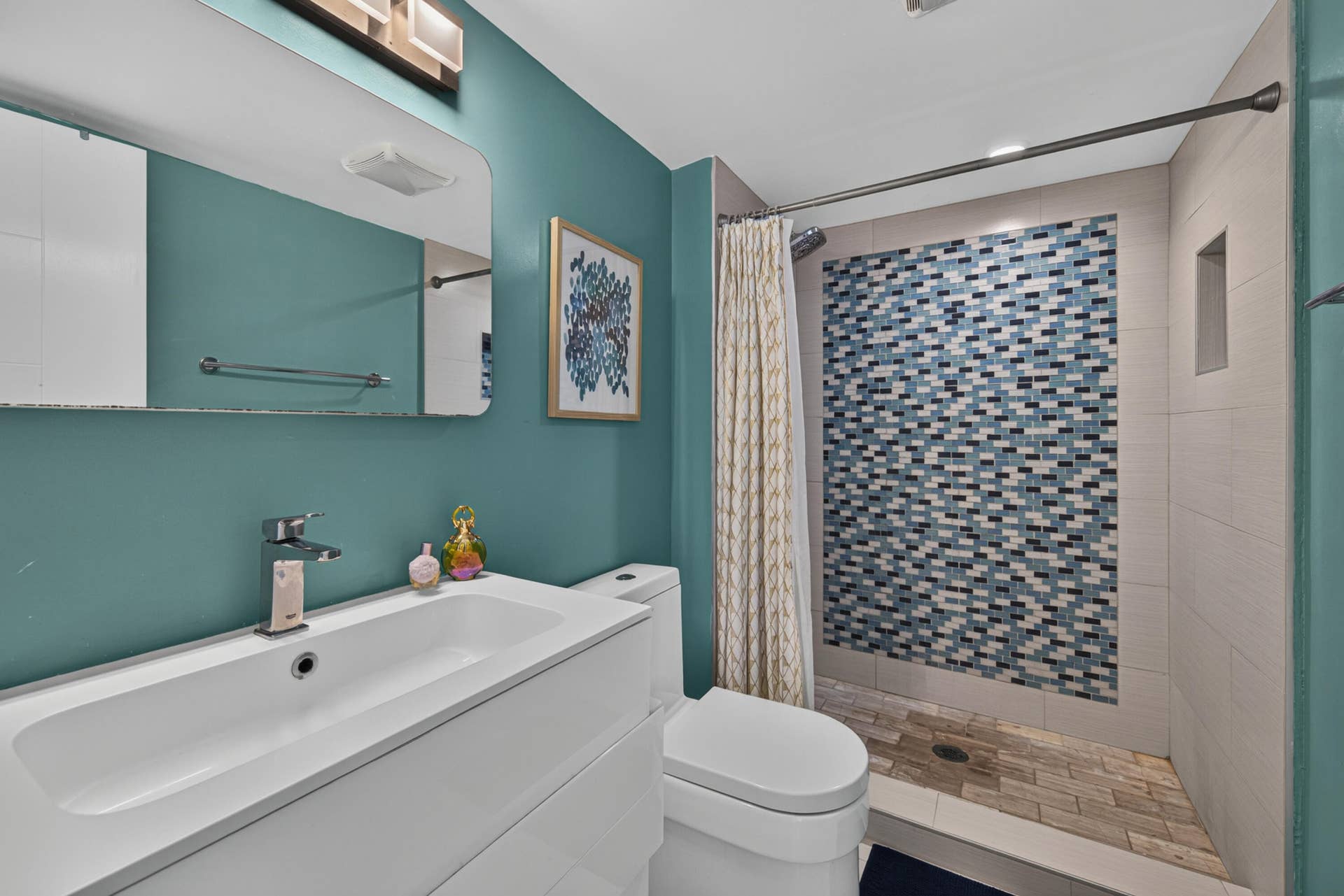 20379 W COUNTRY CLUB Drive, #1139, Aventura, FL 33180 Vanity with integrated sink and chrome faucet, rectangular mirror with integrated lighting, tiled shower with mosaic accent wall, and built-in shower niche