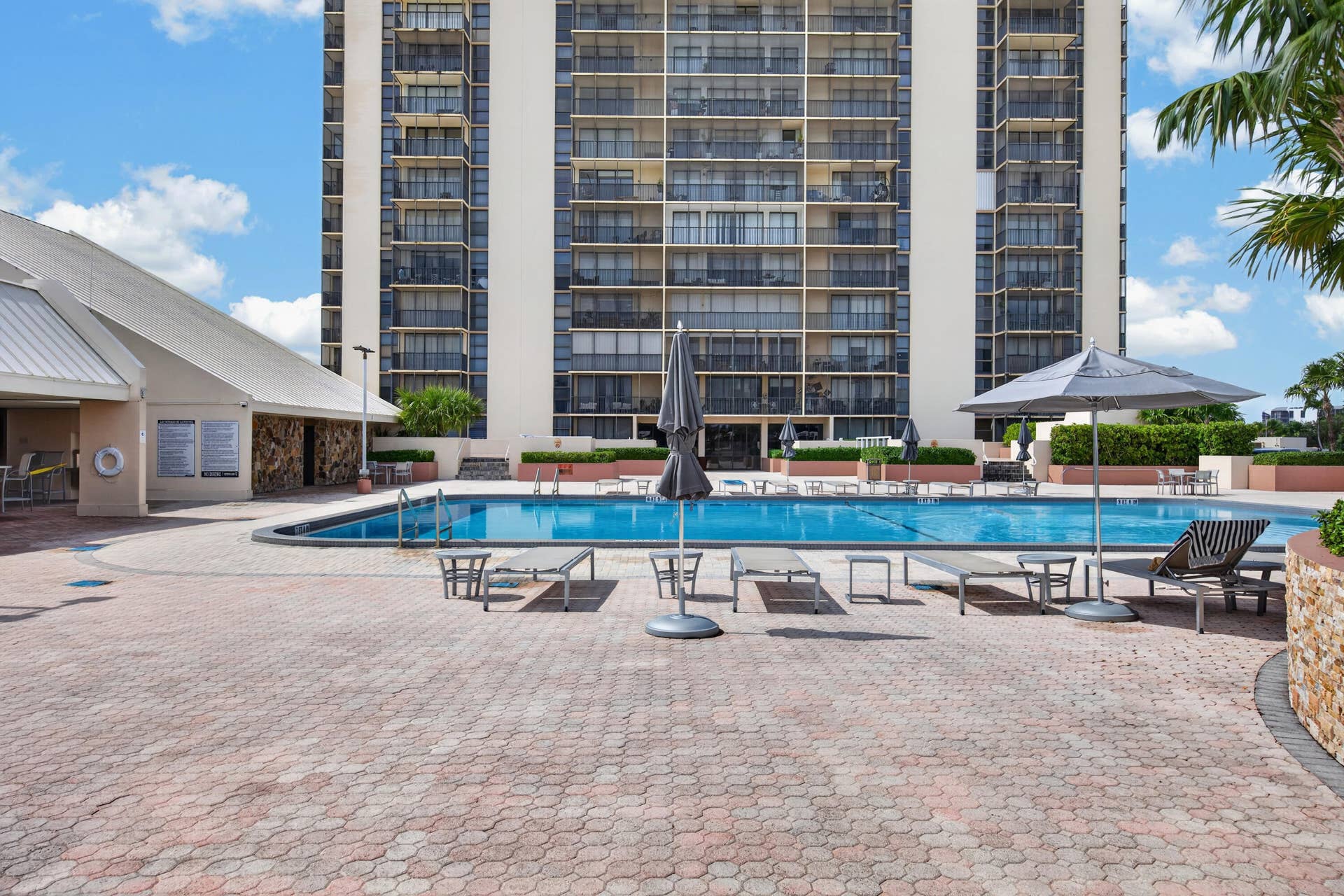 20379 W COUNTRY CLUB Drive, #1139, Aventura, FL 33180 Outdoor pool with a paved deck, perimeter hedging, and a multi-story building exterior