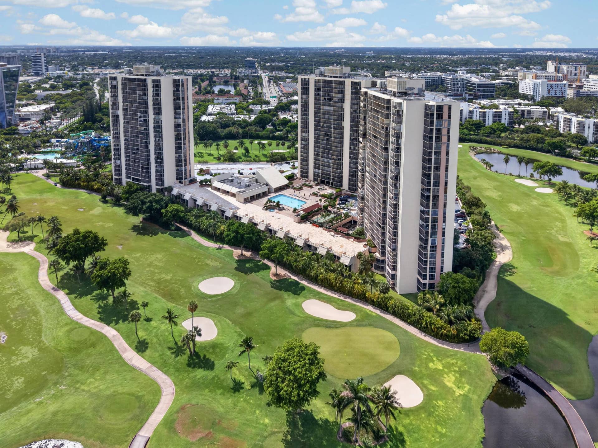 20379 W COUNTRY CLUB Drive, #1139, Aventura, FL 33180 Three high-rise buildings with multiple balconies, a ground-level pool, and surrounding green spaces featuring a golf course and water features