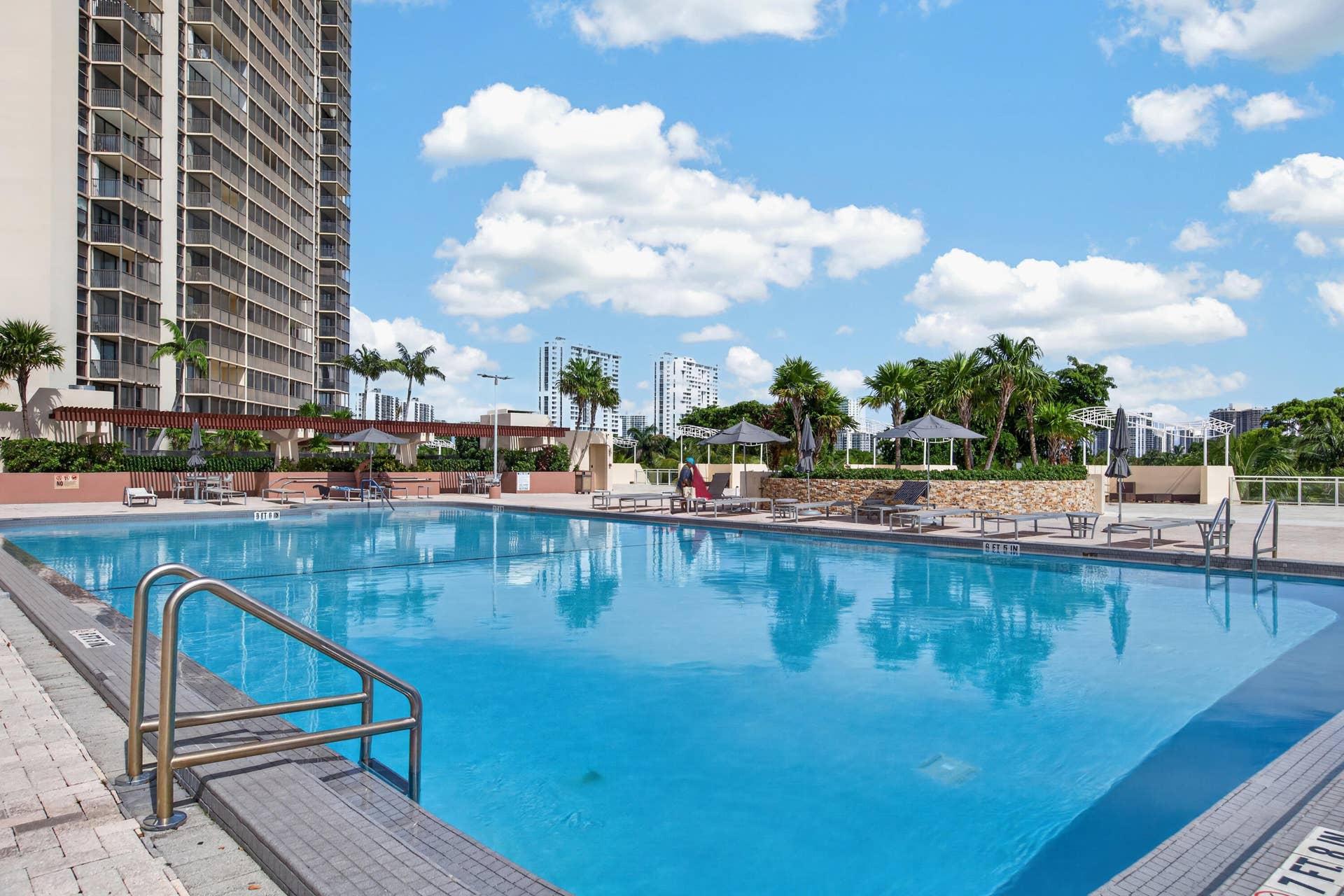 20379 W COUNTRY CLUB Drive, #1139, Aventura, FL 33180 Expansive outdoor swimming pool with integrated entry steps, surrounded by a paved deck and tropical landscaping
