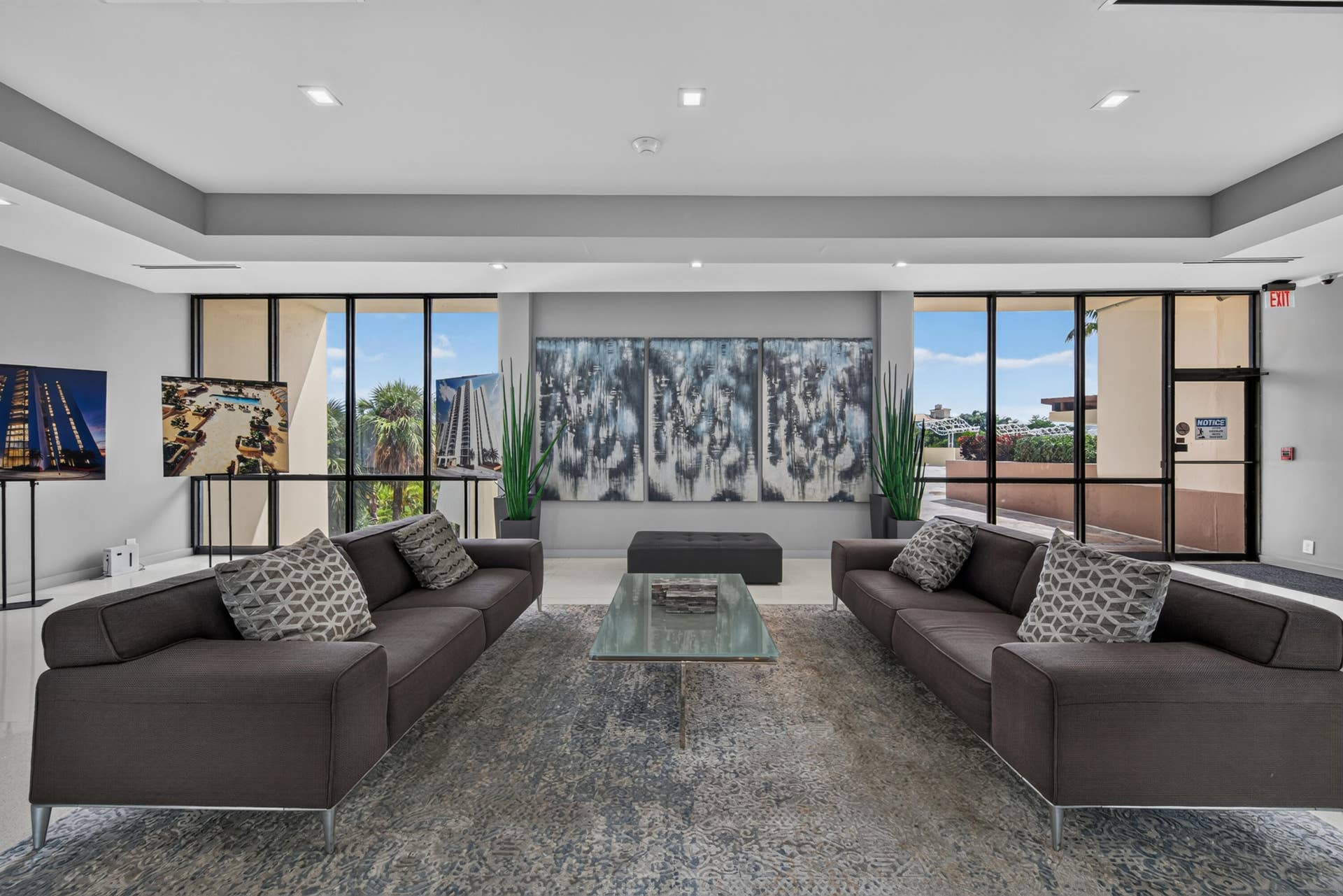 20379 W COUNTRY CLUB Drive, #1139, Aventura, FL 33180 Sophisticated living space anchored by dual charcoal sectional sofas, positioned to maximize the expansive wall of multi-panel glass doors and windows flooding the room with natural light