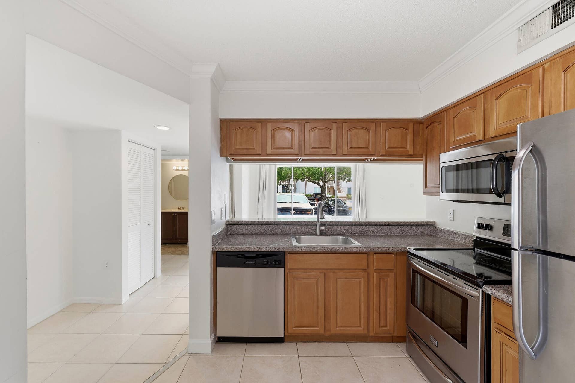 20101 Glenmoor Drive, West Palm Beach, West Palm Beach, FL 33409 Kitchen featuring wood cabinetry, stainless steel appliances, a stone-finish countertop, and tile flooring